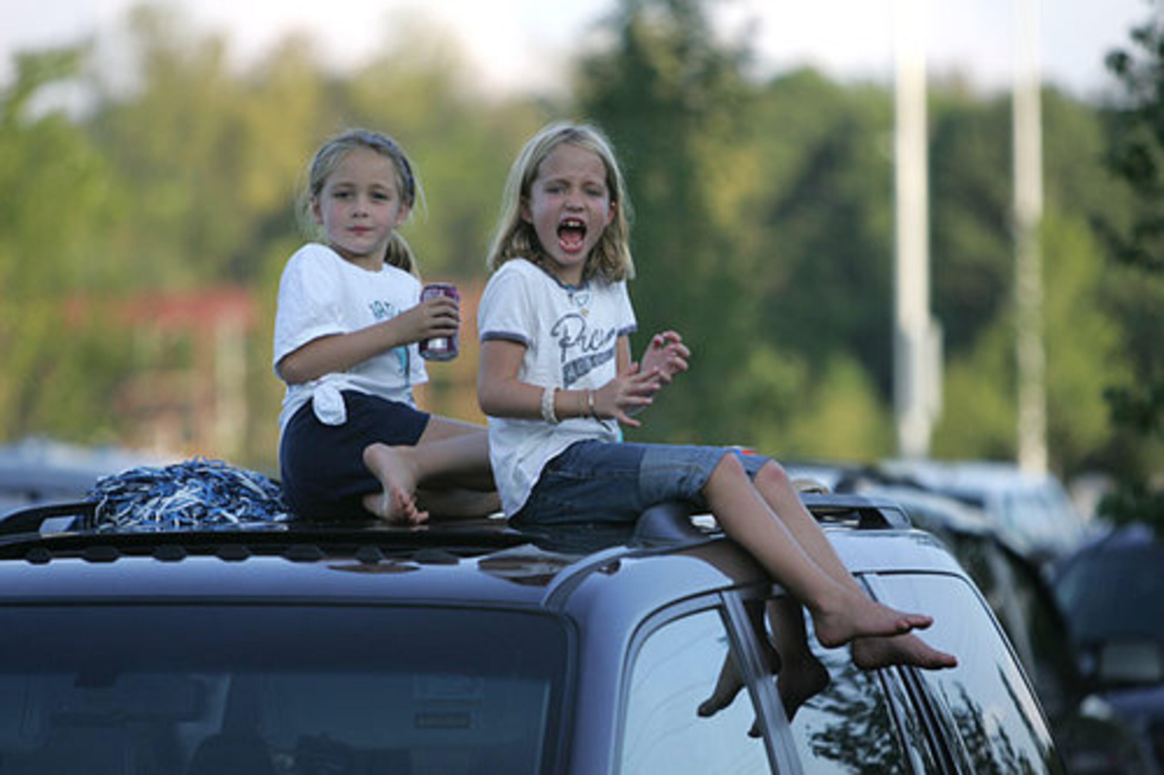 Virginia Hobbs, 7, and Jenny Luetters, 8, hang out on the roof of their parents' car while tailgating for Pace Academy.