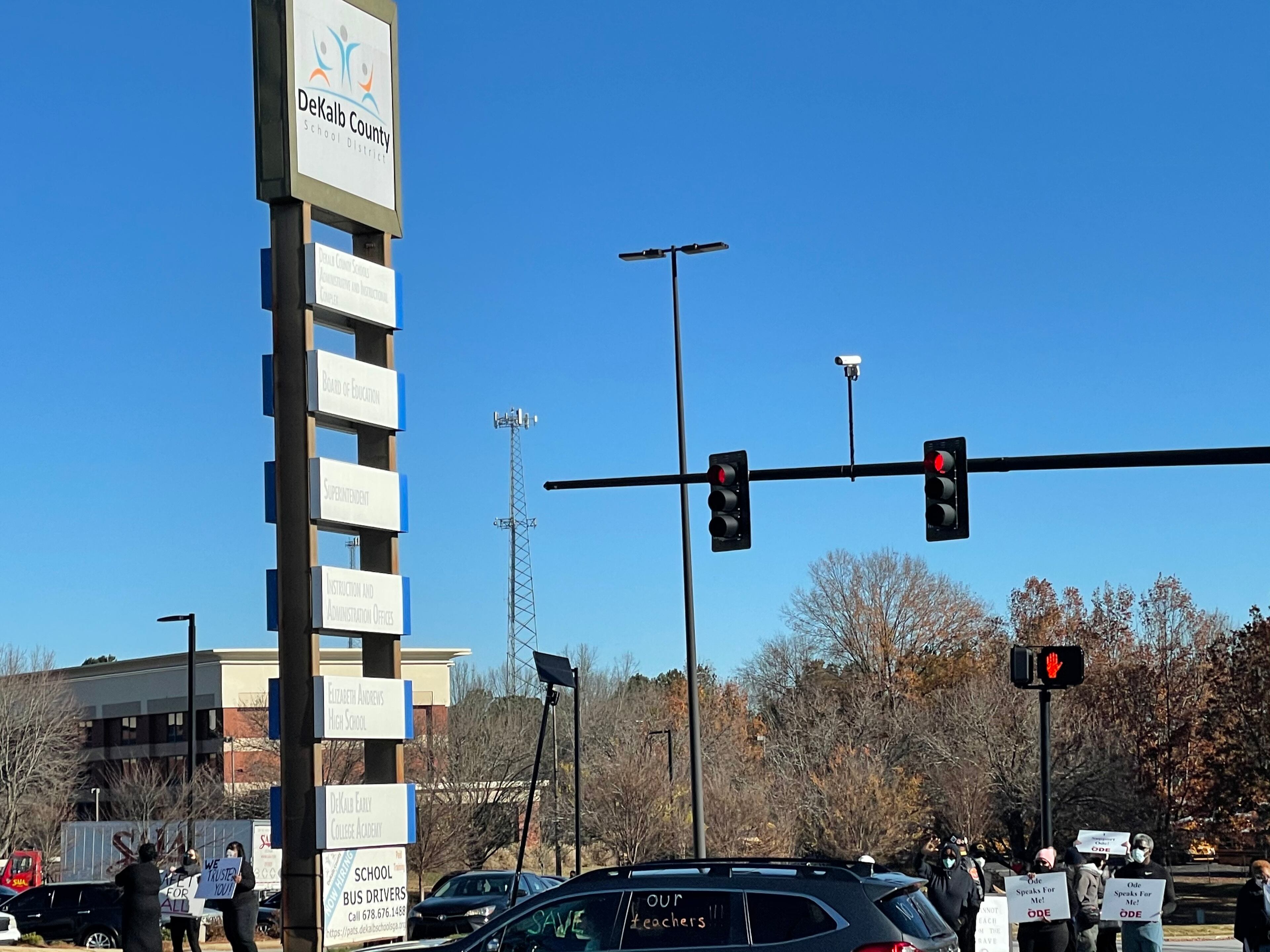 Community members in DeKalb held signs on Tuesday to protest against the reopening of DeKalb County schools.
