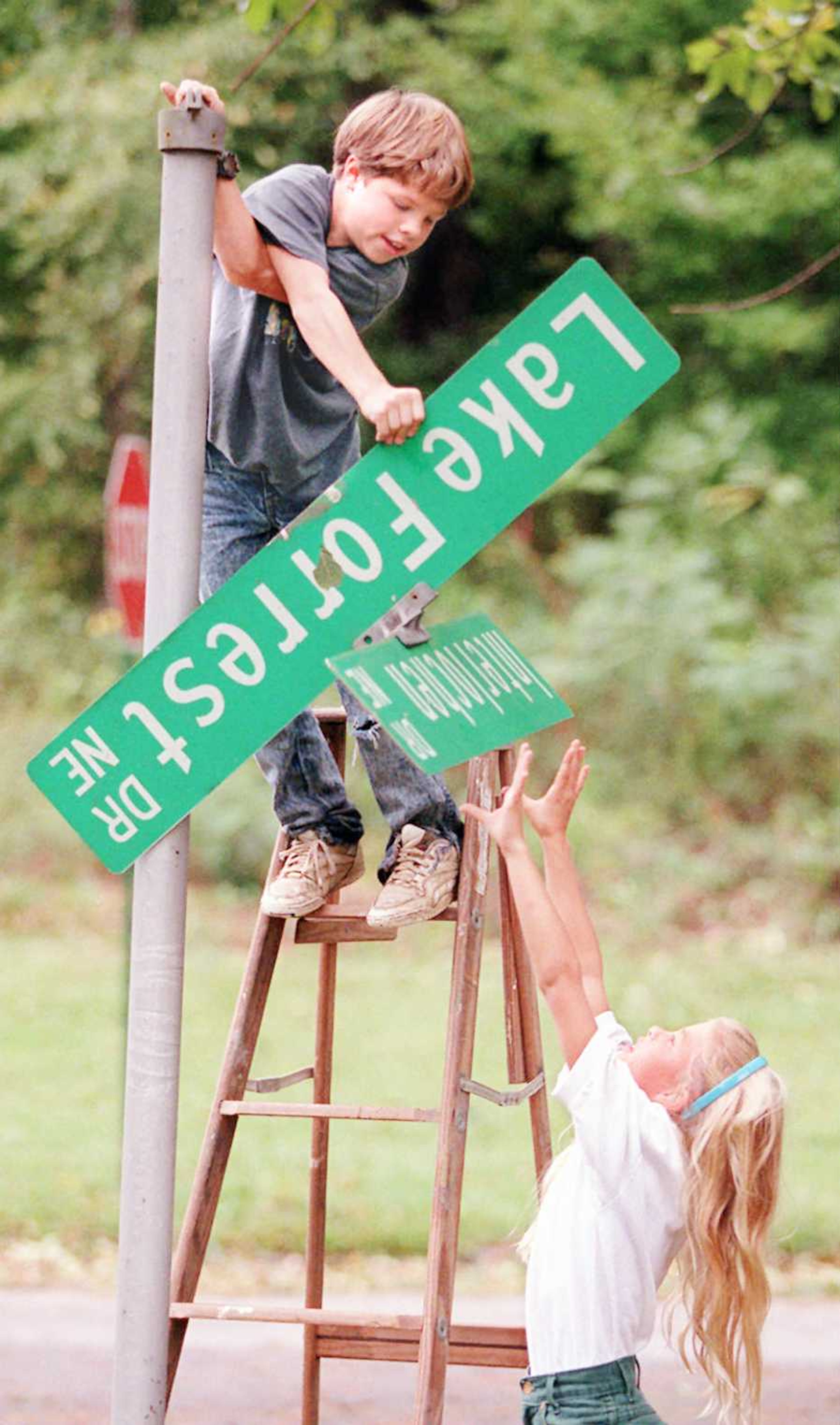 Harrison Young (age 11) hands a broken street sign down to his sister Christian (10) in the aftermath of Hurricane Opal in October 1995. They were trying to replace it but it wouldn't stay.