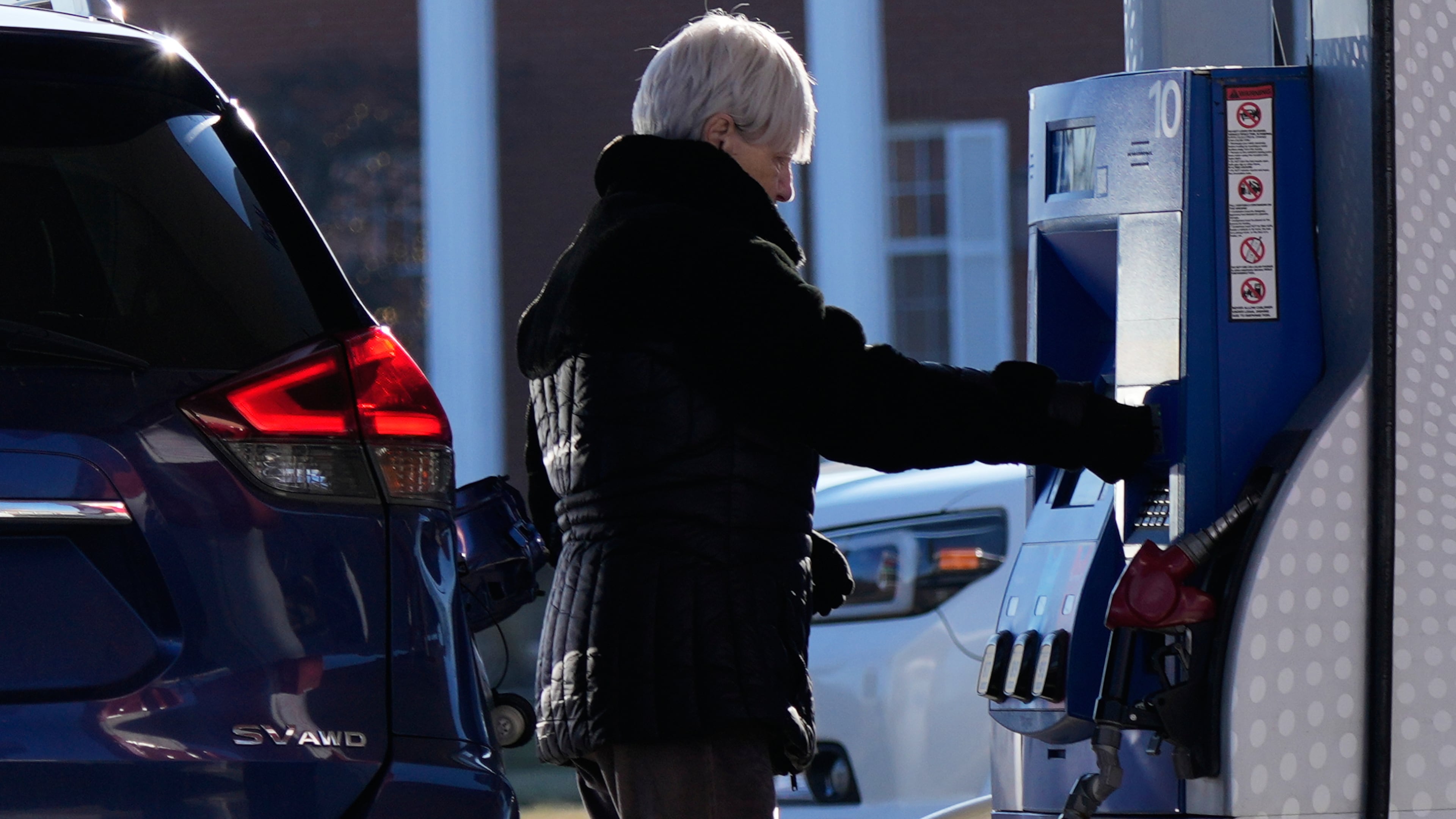 A woman checks gas prices before she fills up her vehicle's gas tank at a gas station in Buffalo Grove, Ill., Wednesday, Jan. 7, 2026. (AP Photo/Nam Y. Huh)