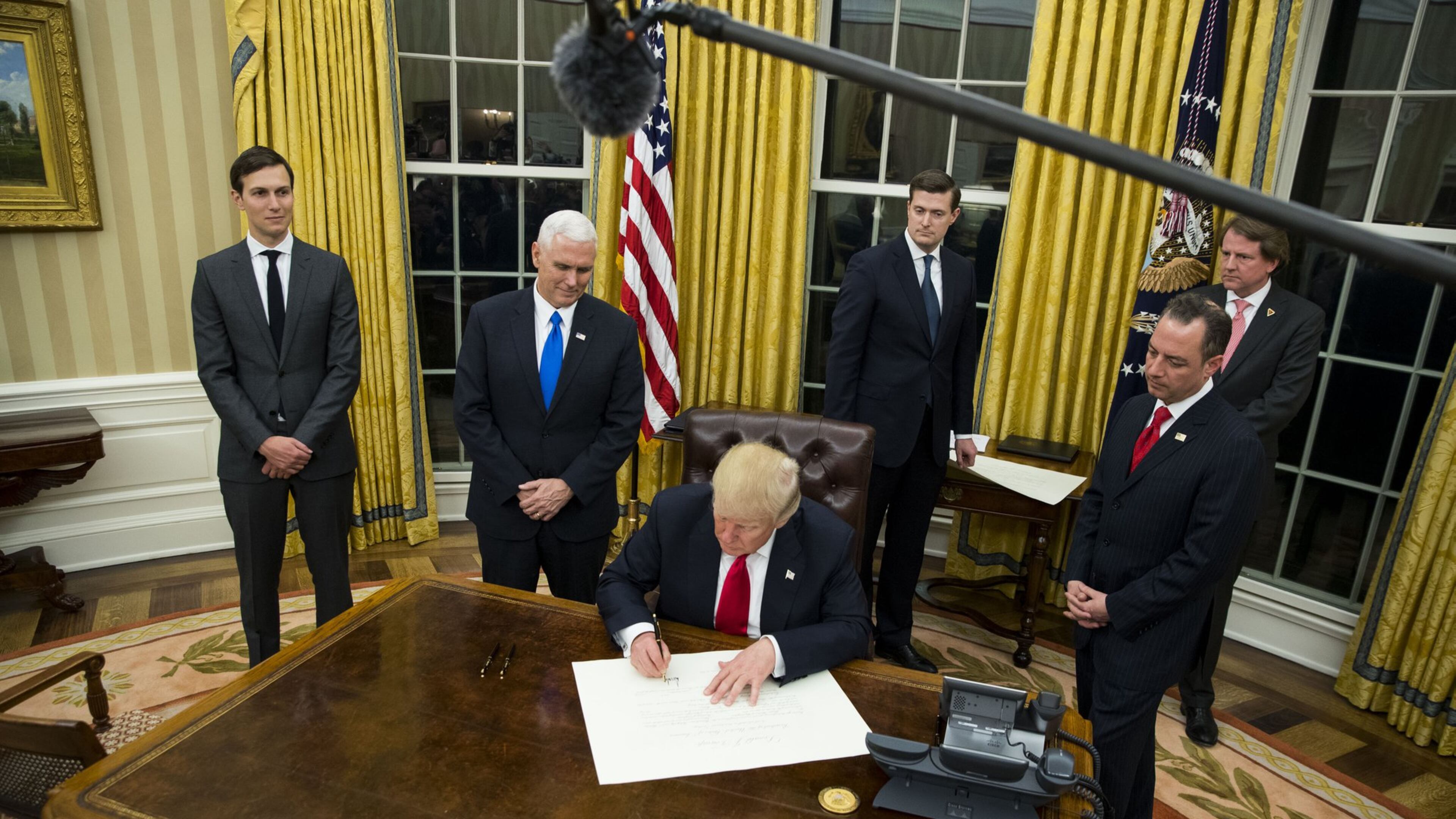 President Donald Trump signs an executive order on his first evening in the Oval Office at the White House in Washington, Jan. 20, 2017. Trump signed a number of executive orders shortly after taking office. At left are Jared Kushner and Vice President Mike Pence. To Trump’s right is Reince Priebus, his chief of staff. (Doug Mills/The New York Times)