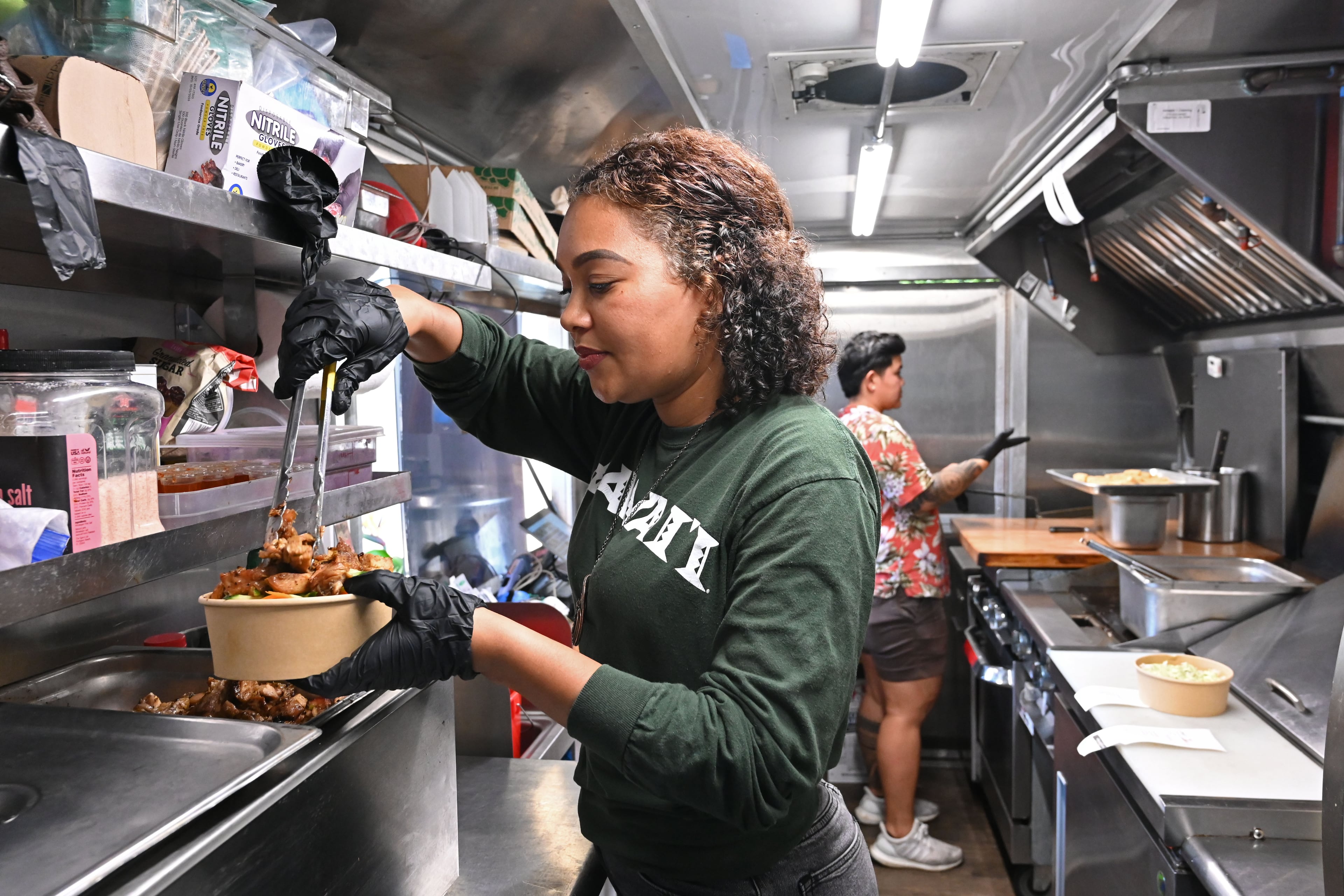 Jess Gorsuch (left) and Sara Siv, owners of Hapa Kitchen, prepare orders inside their food truck at Block & Drum in Chamblee on Wednesday, June 17, 2026. (Hyosub Shin/AJC)