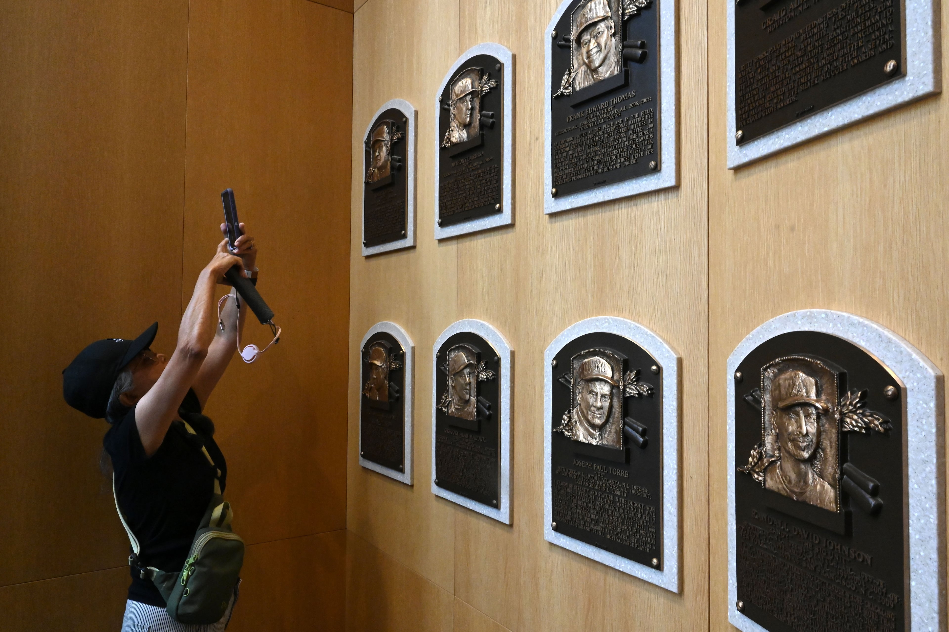 A baseball fan takes a picture of former Braves manager Bobby Cox' Hall of Fame plaque at the National Baseball Hall of Fame and Museum on Friday, July 24, 2026, in Cooperstown, N.Y. Andruw Jones will be inducted into the National Baseball Hall of Fame on Sunday as part of the Class of 2026, alongside Carlos Beltrán and Jeff Kent. He is recognized as one of the greatest center fielders in baseball history. Jones will become the 12th player with ties to the Atlanta Braves to be inducted into the Hall of Fame. (Hyosub Shin/AJC)