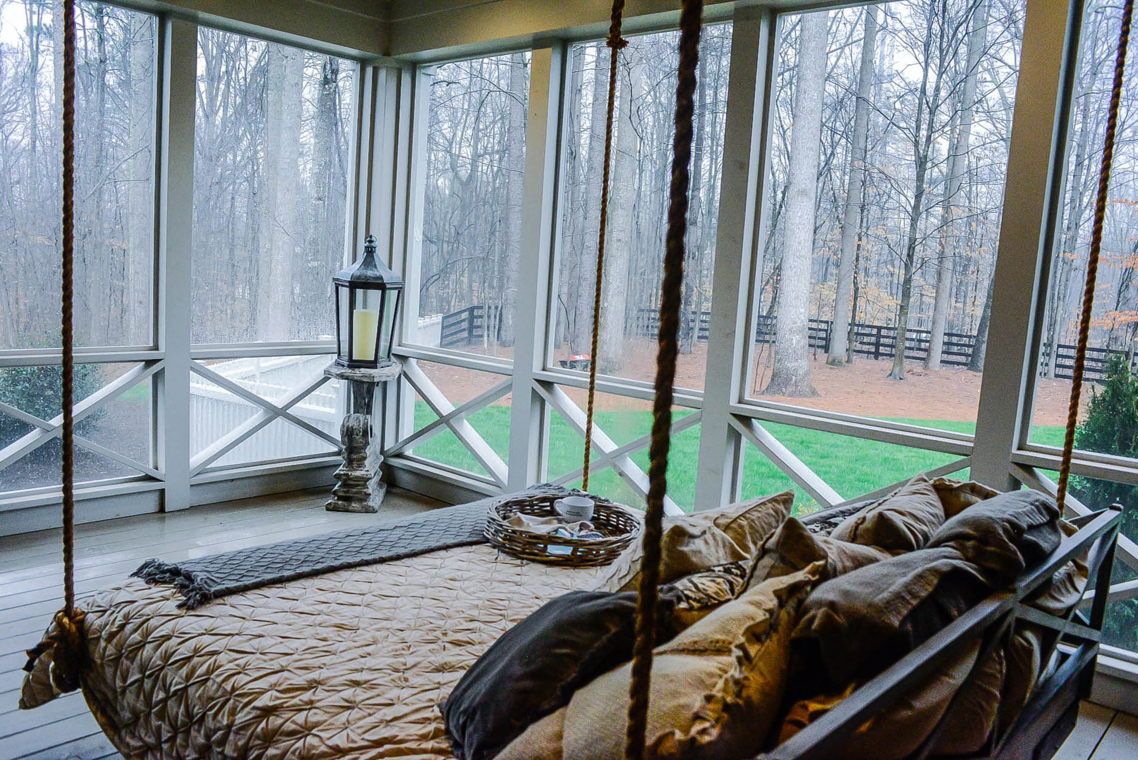 A swing bed is suspended from the ceiling with rope on the screened porch. It gives the Canton homeowners a comfortable perch to see the surroundings.