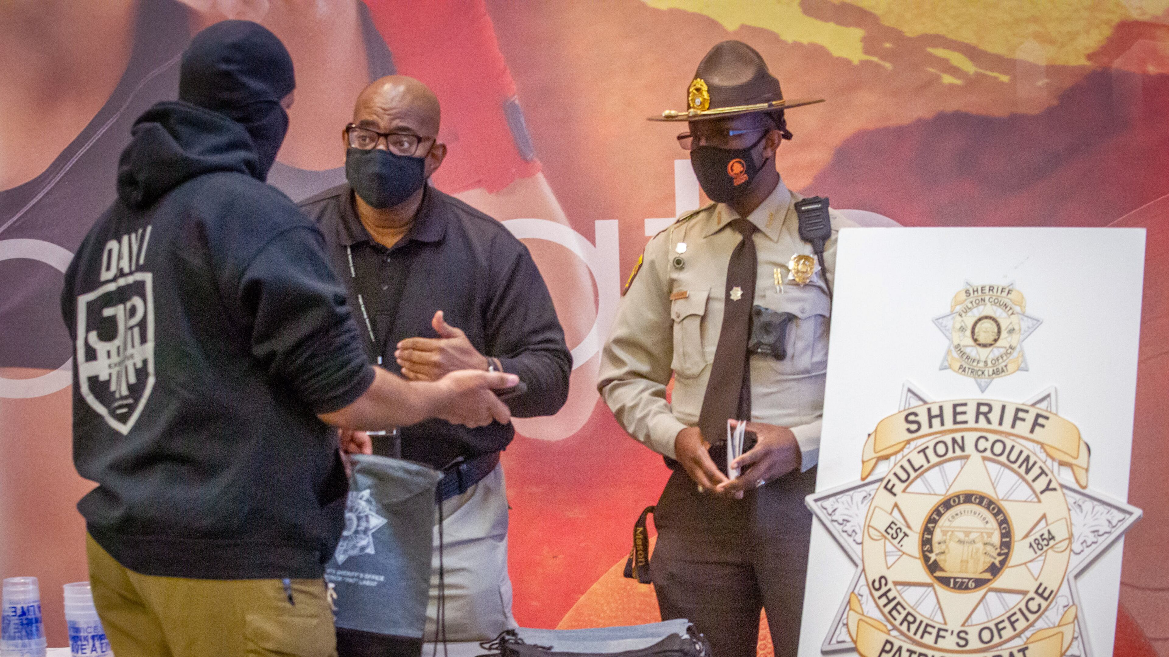 Tommy White (C) and Detention officer Rayshaun Clark talk with Robert Richardson at a Fulton County Sheriff's Office job fair at LA Fitness in Atlanta Friday, February 11, 2022. STEVE SCHAEFER FOR THE ATLANTA JOURNAL-CONSTITUTION
