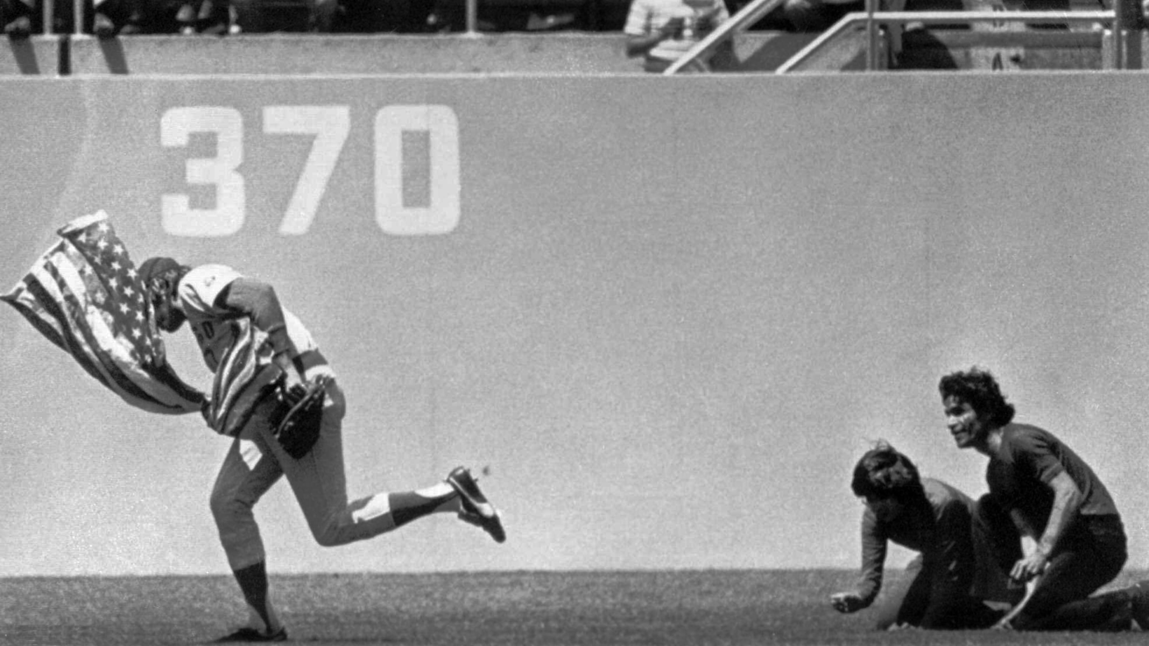 FILE - Outfielder Rick Monday of the Chicago Cubs dashes between two men in the Dodger Stadium Outfield in Los Angeles, in this April 25, 1976 photo, snatching an American flag the men were about to burn. (AP Photo/Los Angeles Herald Examiner, James Roark,File)