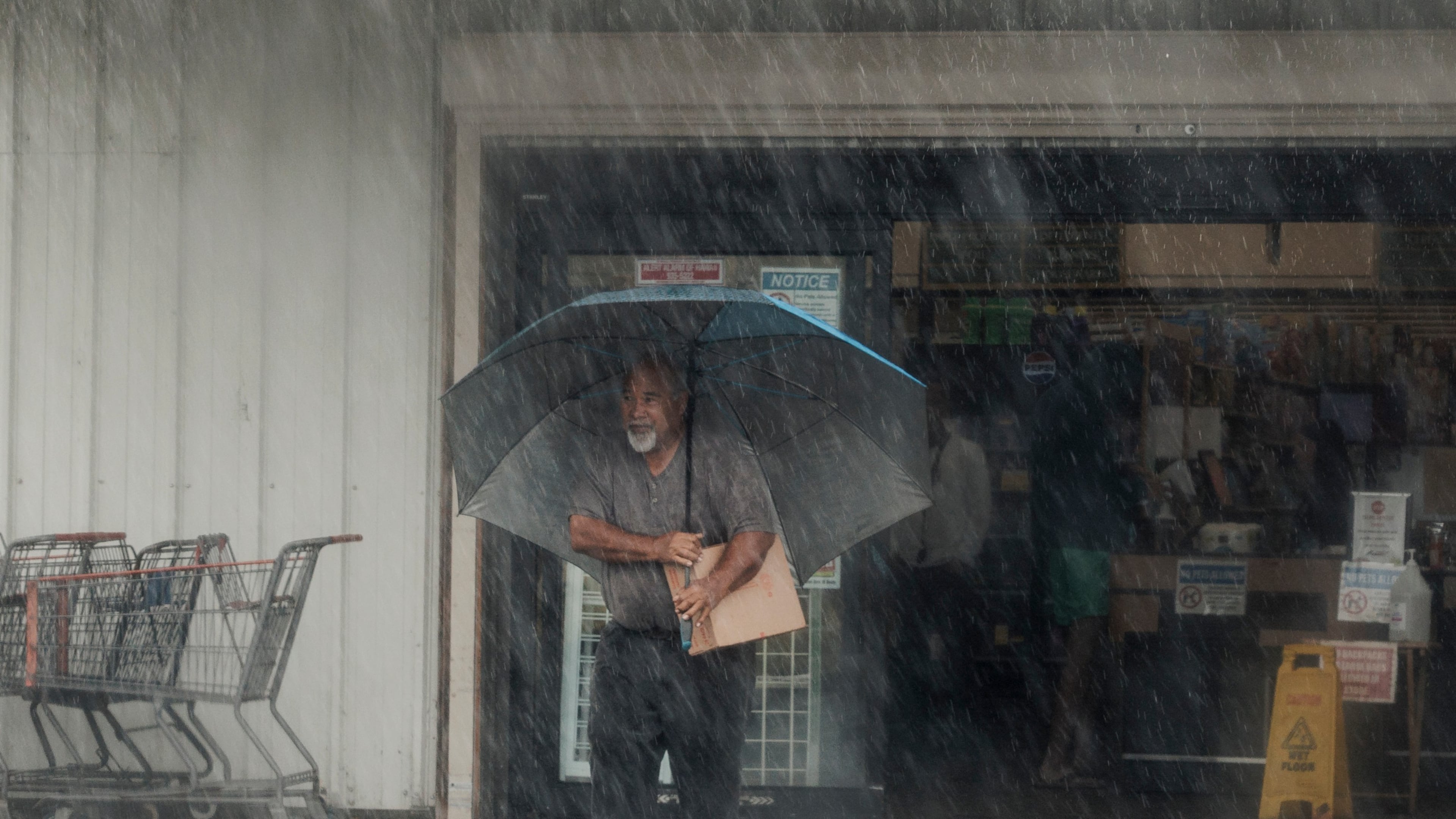 A resident carries supplies during Hurricane Lala in Hawaiian Ocean View, Hawaii, Saturday, Aug. 15, 2026. (Stephen Lam/San Francisco Chronicle via AP)