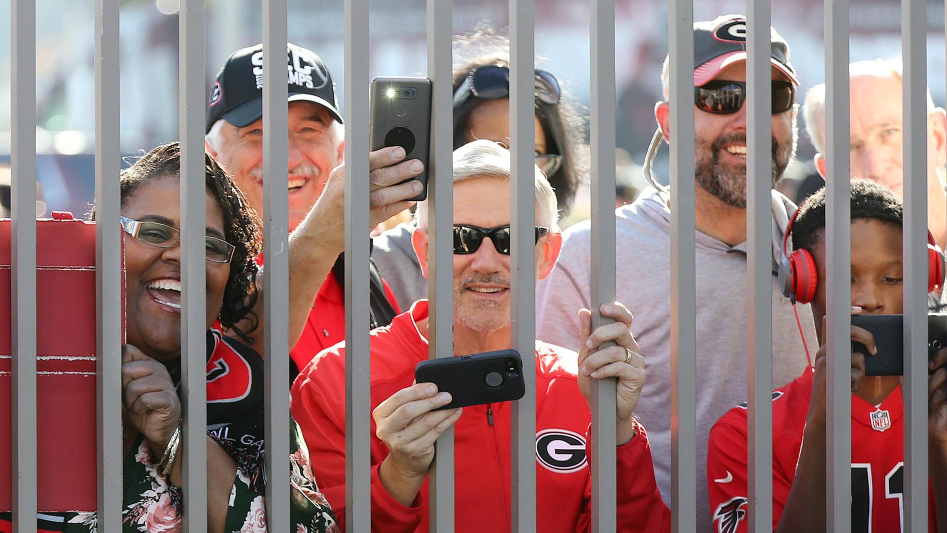 Georgia fans angle for a view and snap photos through the fence while the Georgia official team photo is taken at Rose Bowl Stadium on Sunday, December 31, 2017, in Pasadena. Curtis Compton/ccompton@ajc.com
