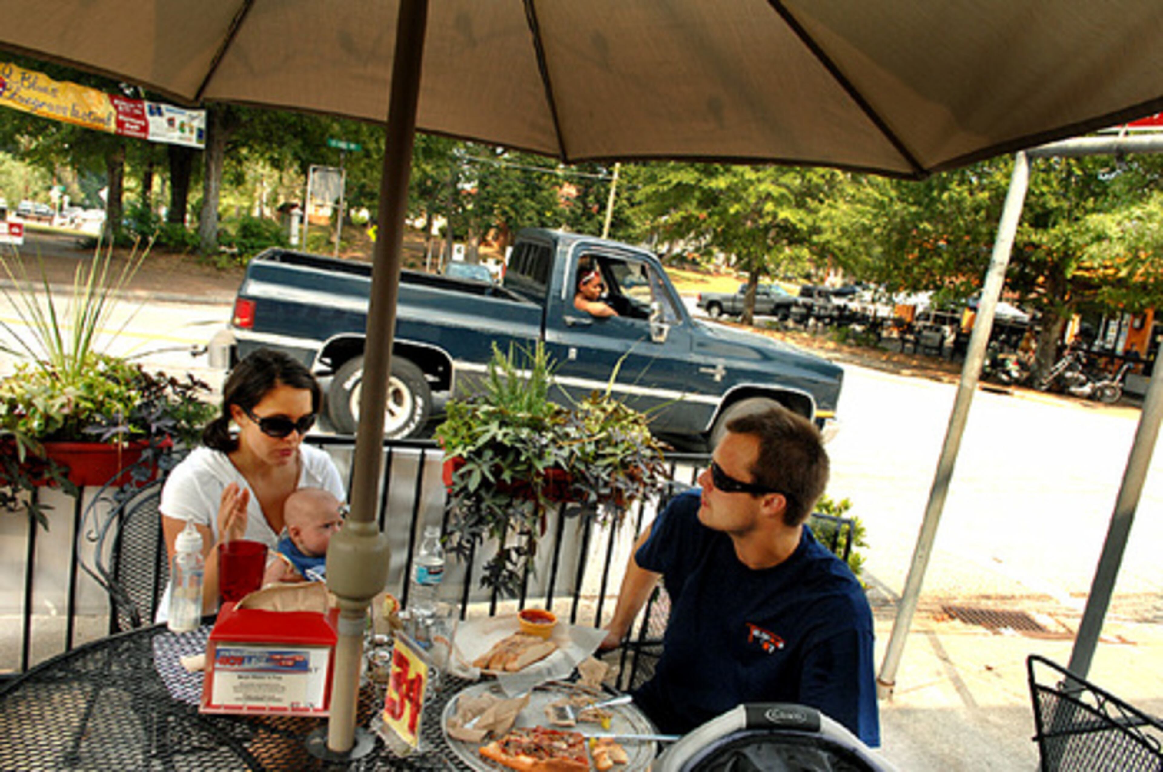 Katie Barton (left) and Spencer Barton, with their 4-month-old baby Blake, enjoy a pizza at Mojo Pizza in the business district.