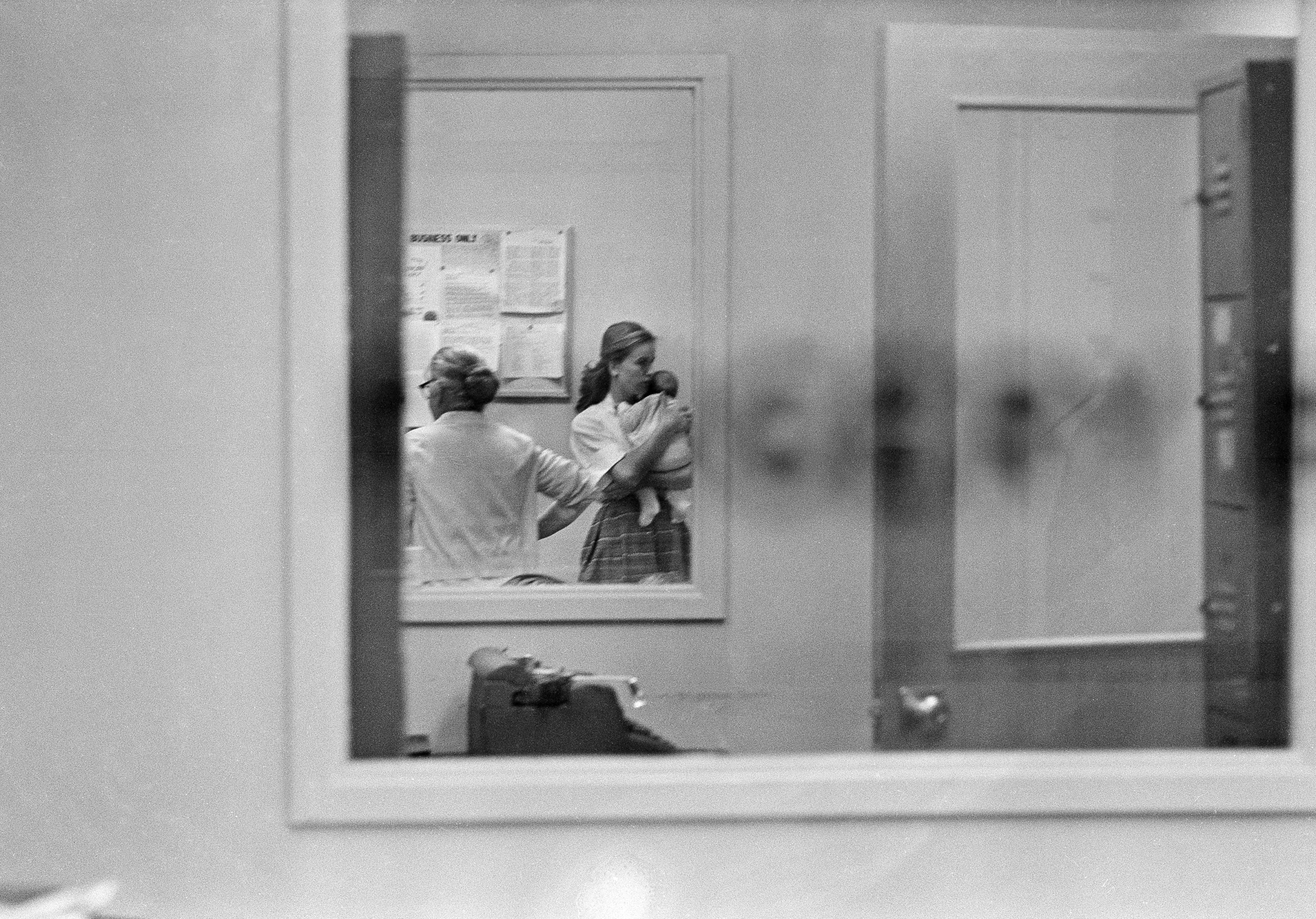 Marina Oswald and her mother-in-law, Marguerite Claverie Oswald, are seen through a window at the Dallas police station where her husband, Lee Harvey Oswald is being held in the assassination of U.S. President John F. Kennedy, Nov. 22, 1963. Marina is holding her 5-week-old daughter, Rachel. (AP Photo)