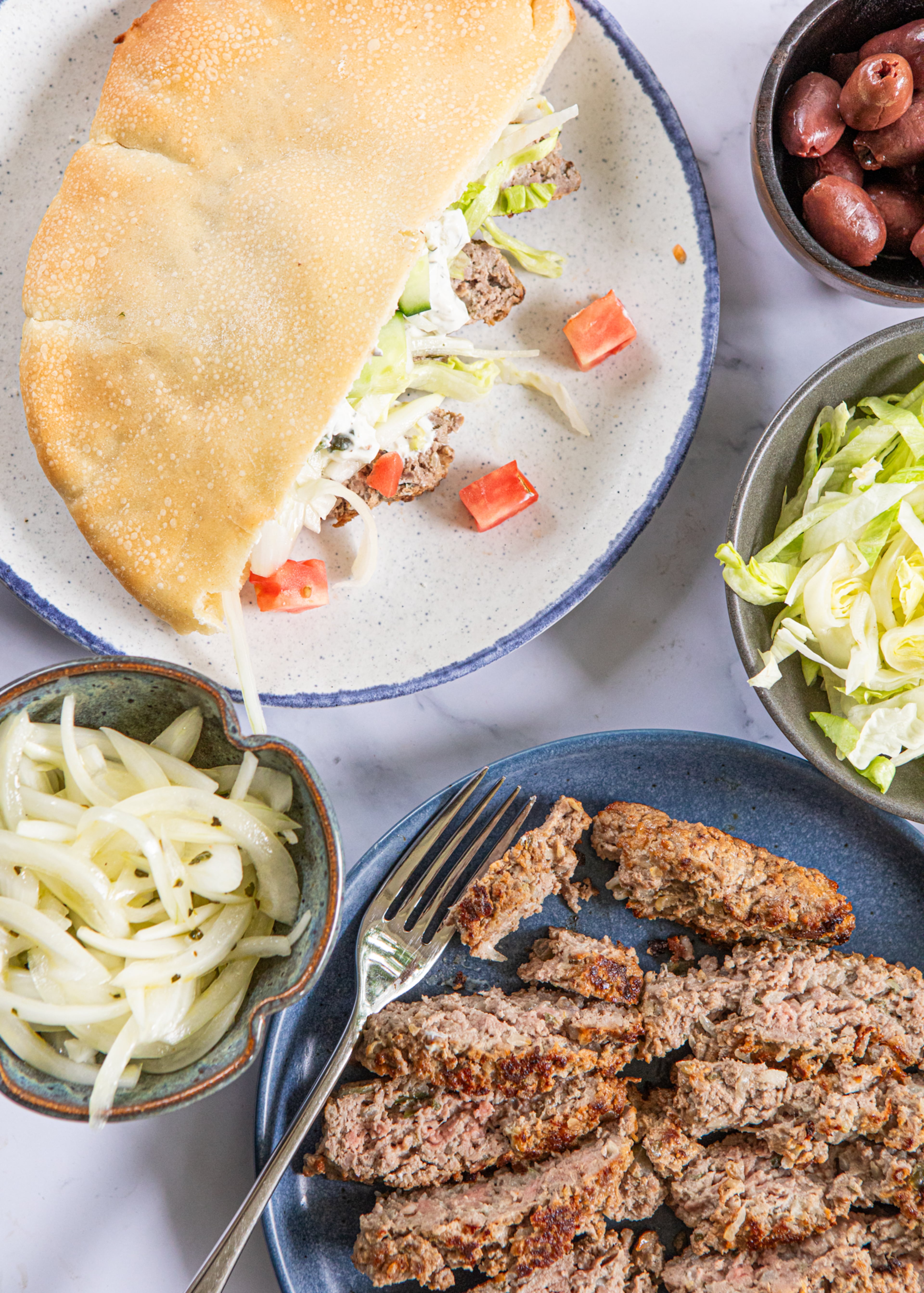 Quick Lamb Gyros can be served like a taco bar. Bring out the meat, onions, pita, sauce and other toppings, and let everyone build their gyros just as they’d like. (Aaliyah Man for the AJC/food styling by Kate Itrich-Williams)