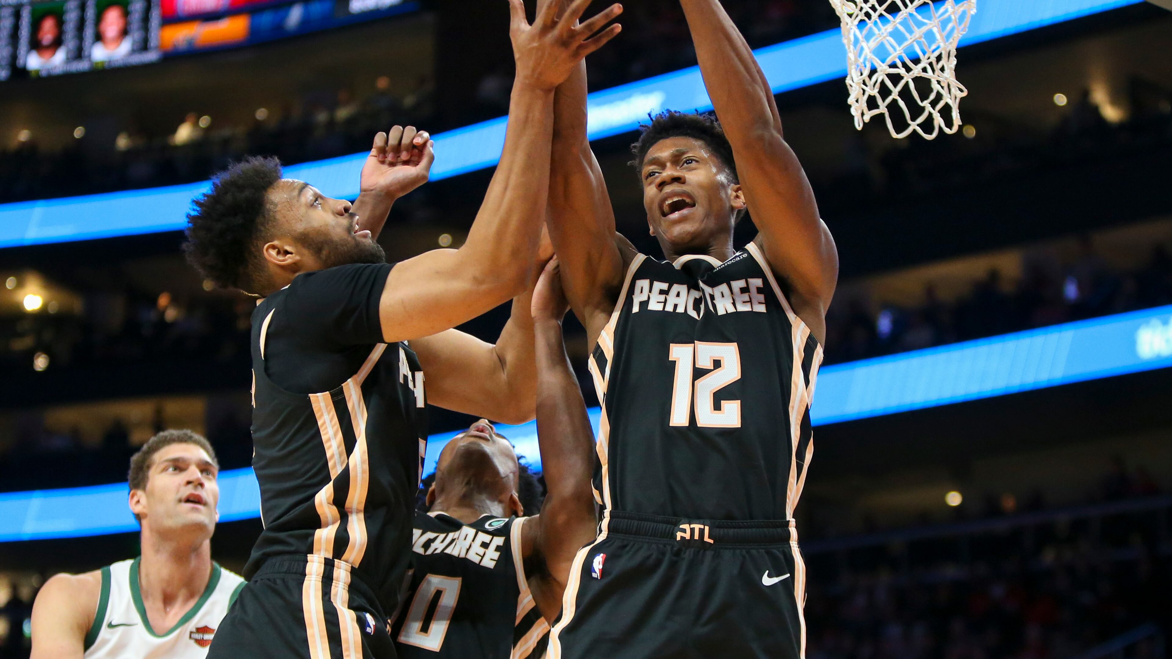 Atlanta Hawks forward Jabari Parker (5) and forward De'Andre Hunter (12) reach for a rebound against the Milwaukee Bucks in the first half of an NBA basketball game, Wednesday, Nov. 20, 2019, in Atlanta. (AP Photo/Brett Davis)