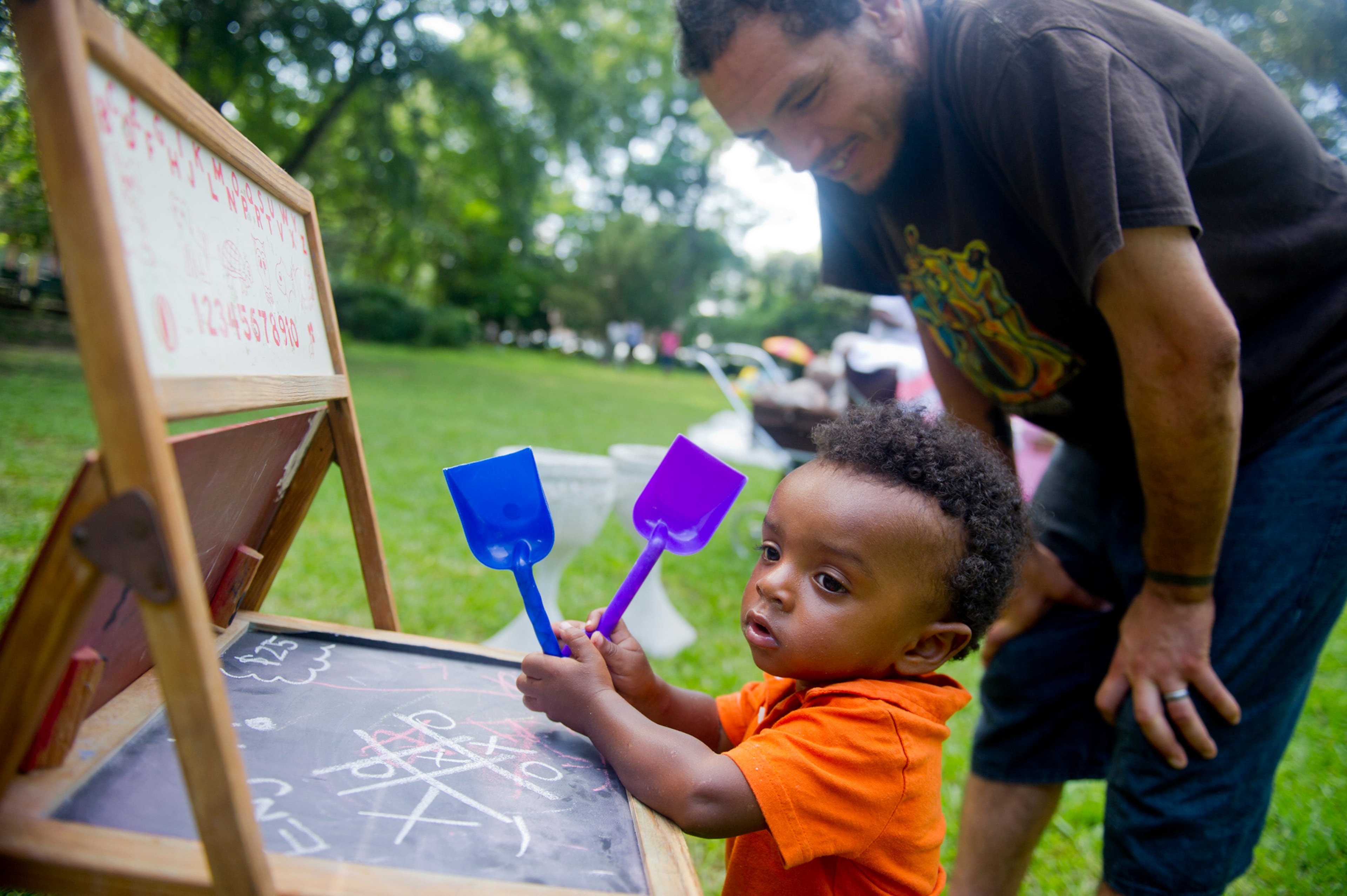 Otis Stone (left) plays with an antique chalk board as his father Nate stands over him at the Town Meets Country pop-up market at the Wren's Nest in Atlanta on July 28, 2013.