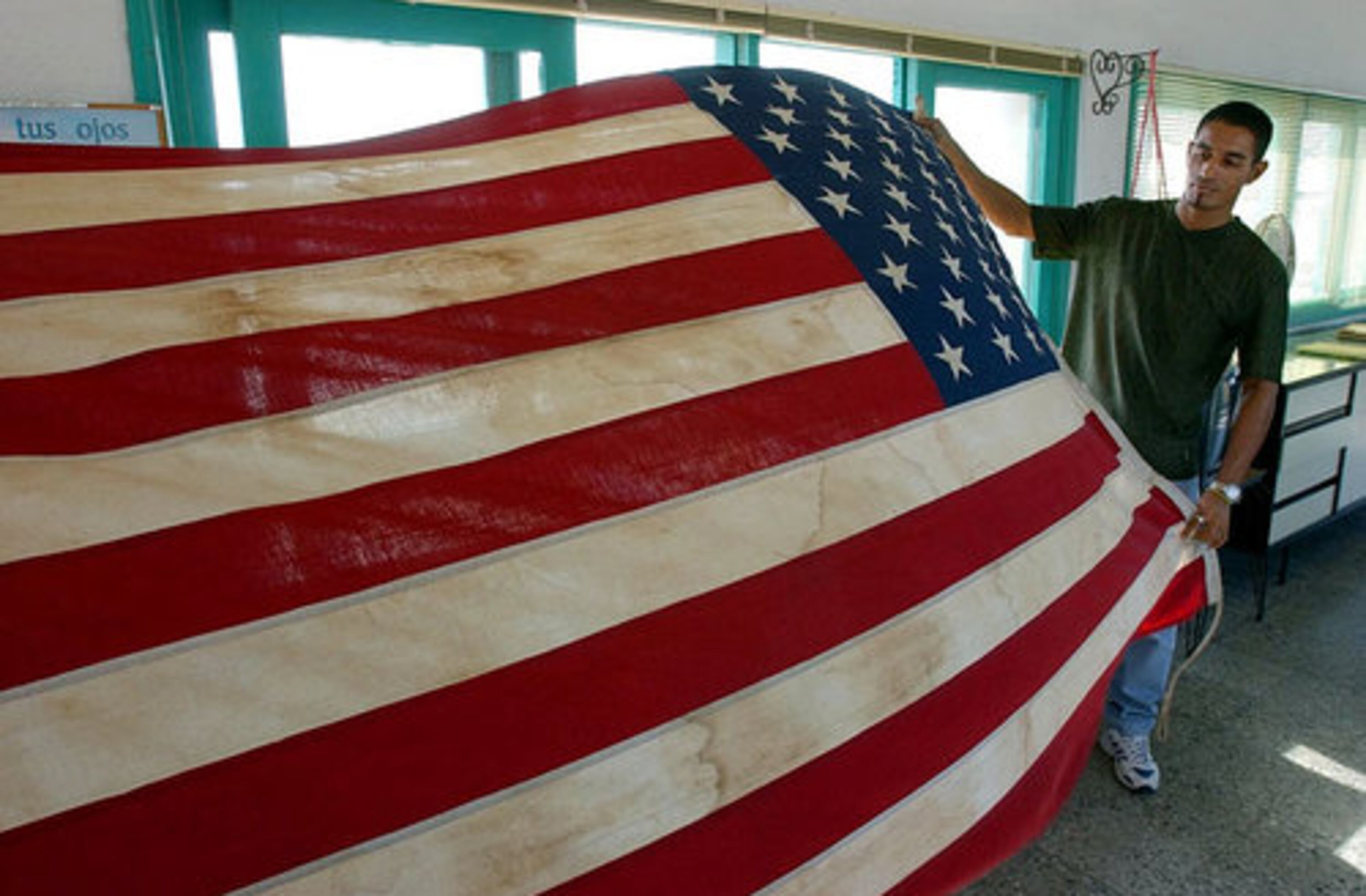 Is this a sign of things to come? Back in 2002 Havana port traffic manager Barbaro Gonzalez unfurls the weathered American flag that has not been used in 50 years now.