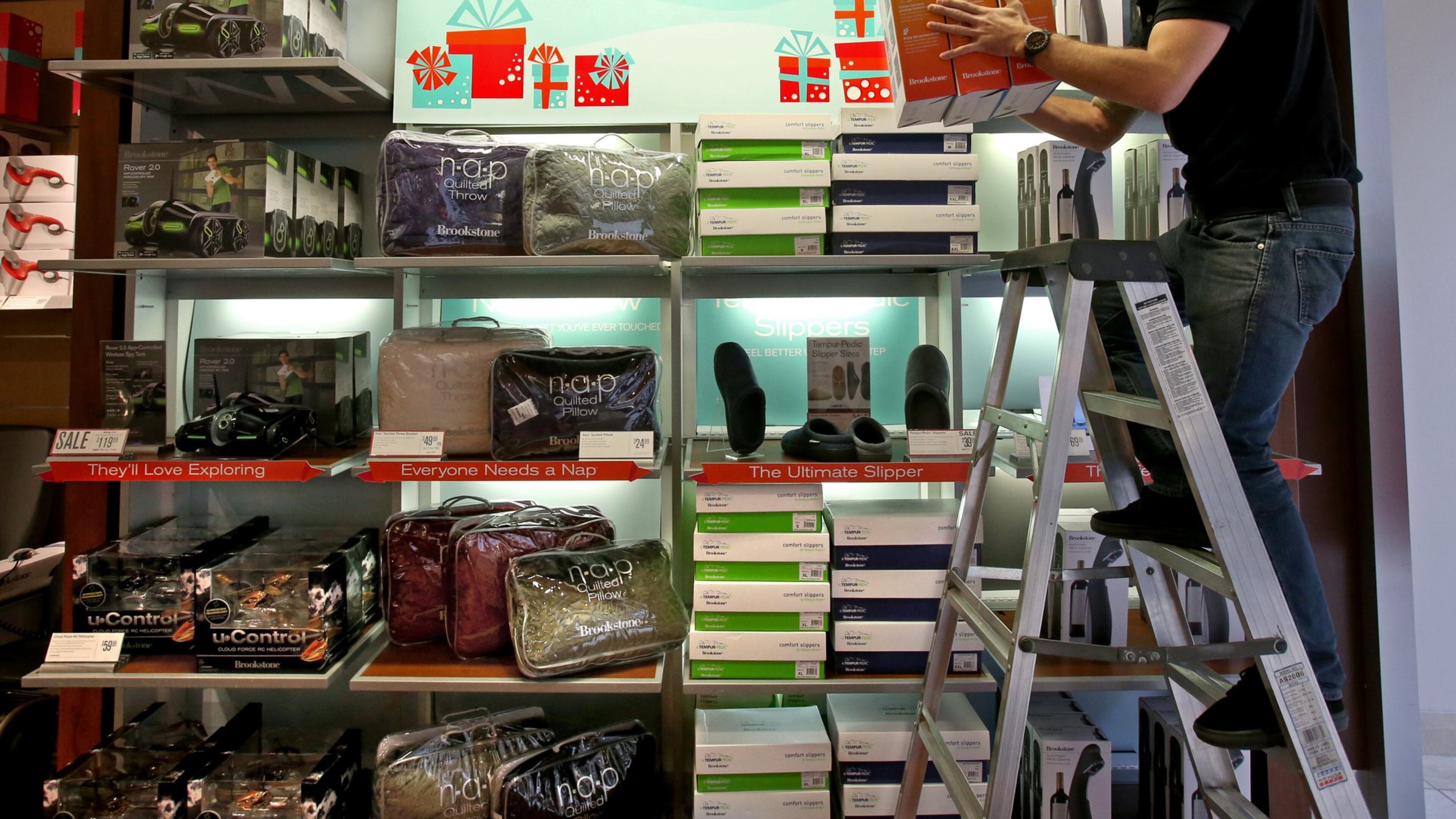 Brookstone sales associate Cody Riggs works on building a display of highlighted products in preparation for the rush of business Thursday night at the Town Center Wednesday morning in Kennesaw, Ga., November 27, 2013. The new trends in holiday shopping have created a cultural shift where shoppers head to stores for Thursday night shopping.