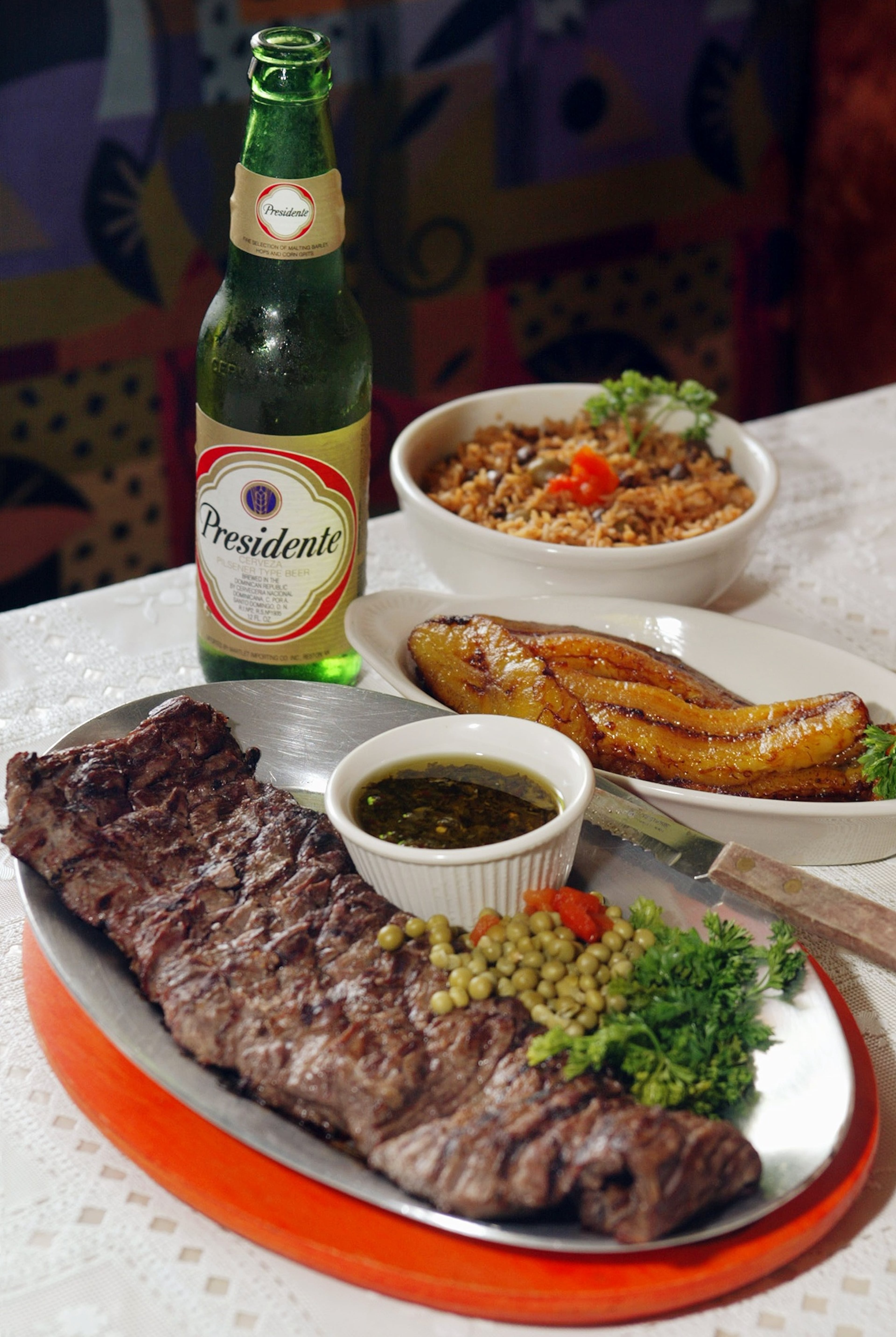 This photo of the churrasco (grilled steak) with chimichurri sauce, Puerto Rican rice, maduros and a Presidente beer is from Monti Carlo's mother's restaurant, Caribbean Grill in Roswell. Carlo credits that AJC review with keeping the restaurant in business. (Phil Skinner/AJC file photo)