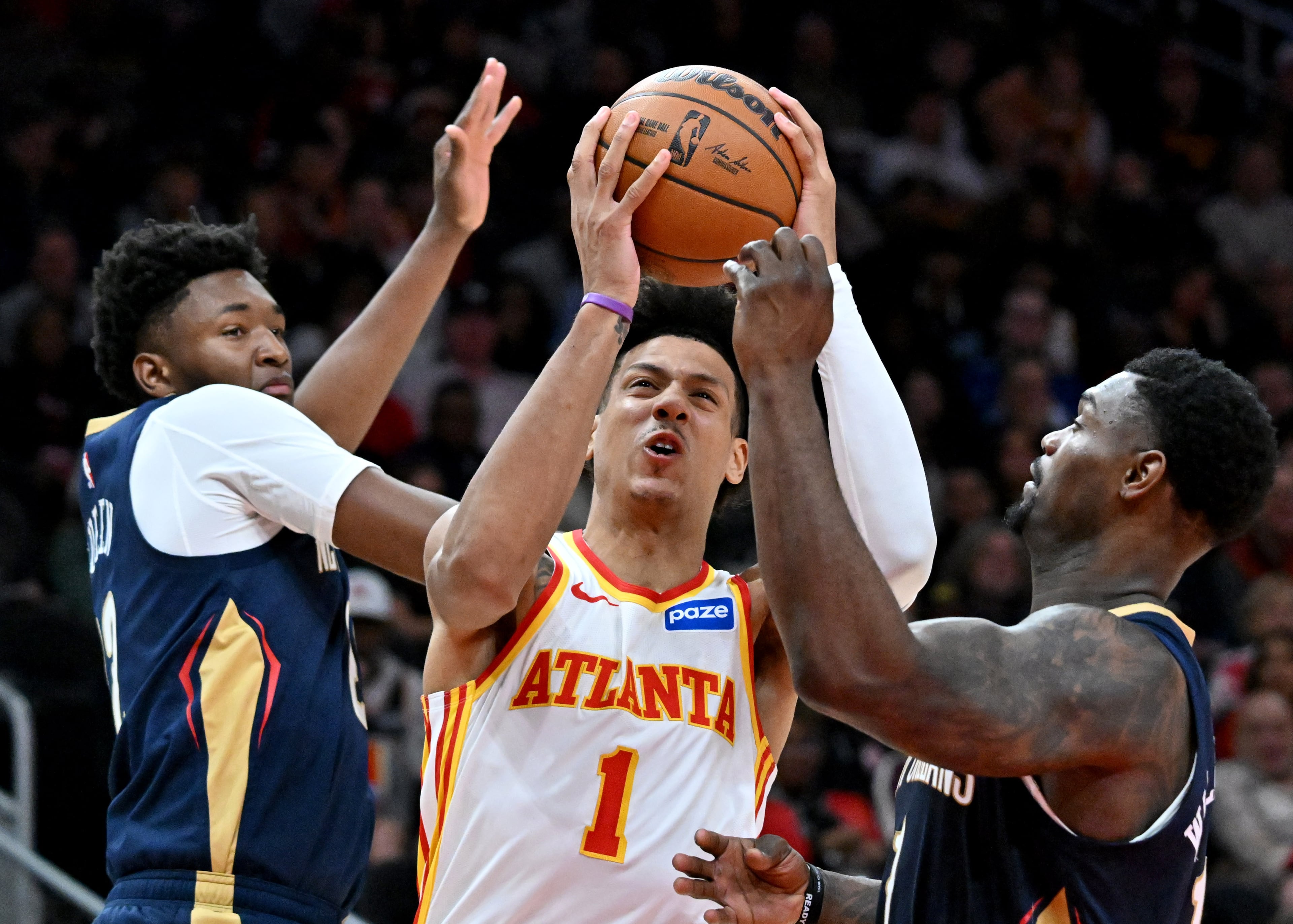 Atlanta Hawks forward Jalen Johnson (1) drives against New Orleans Pelicans center Derik Queen (left) and New Orleans Pelicans forward Zion Williamson (right) during the first half in an NBA basketball game at State Farm Arena, Wednesday, Jan. 7, 2026, in Atlanta. (Hyosub Shin/AJC)