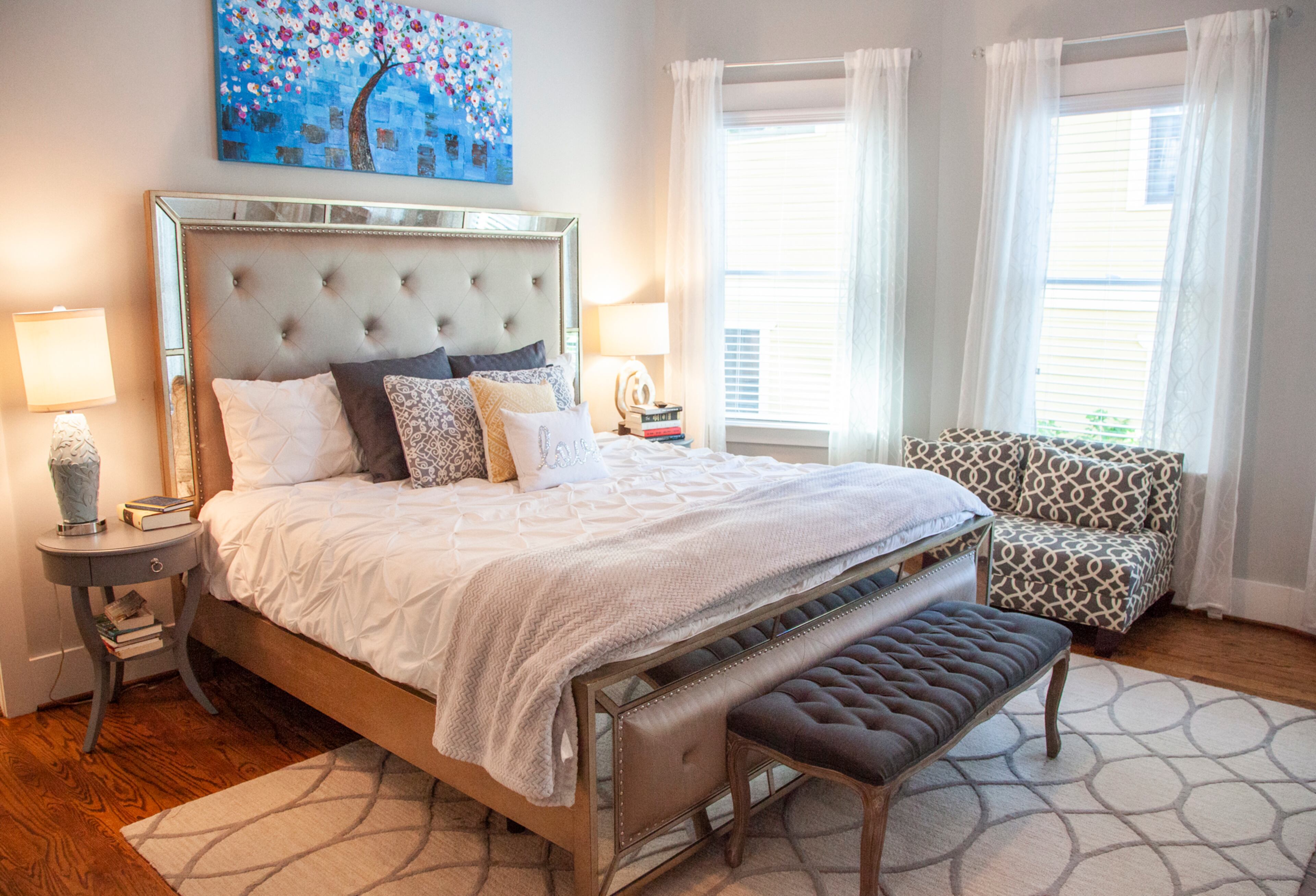 Brad and Brigette Doss knew they wanted to keep their master bedroom clean and bright, so they chose furniture from Macy's, a rug from HomeGoods and a window seat from Wayfair in neutral hues. Original art by Grace Smith hangs over the bed, balancing the white bedding and muted palette of the room with a pop of color.
