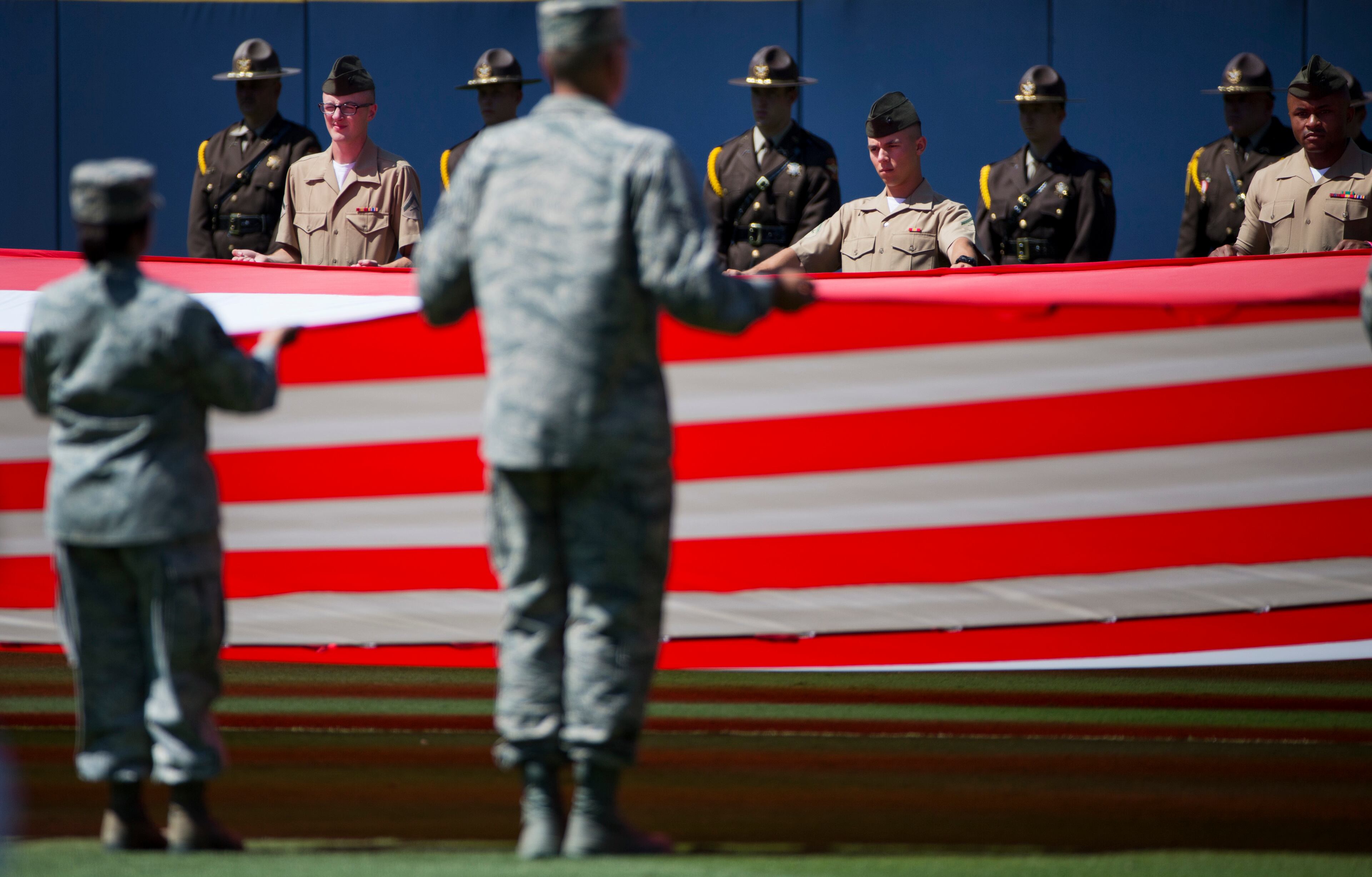 Members of the U.S. military stand at attention while unveiling a giant American flag in the outfield at a Memorial Day ceremony before the start of a baseball game between the Atlanta Braves and the Milwaukee Brewers Saturday, May 23, 2015, in Atlanta. (AP Photo/David Goldman)