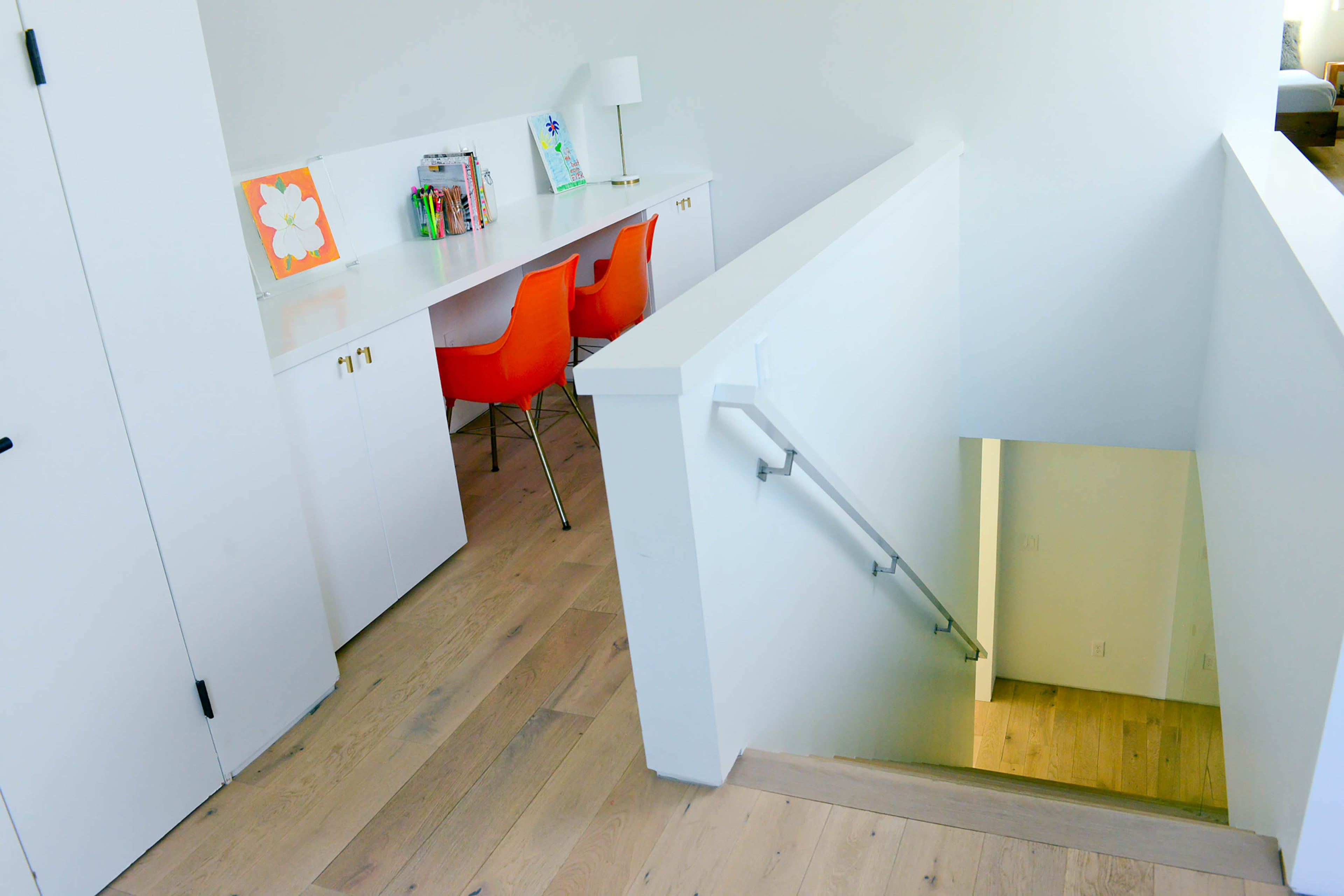Built-in storage helps the family of five stay organized and keeps clutter at bay. Throughout the Brookwood Hills home, walls painted Benjamin Moore Super White form a blank canvas that allows colorful accessories, like the bright orange chairs, to stand out.
