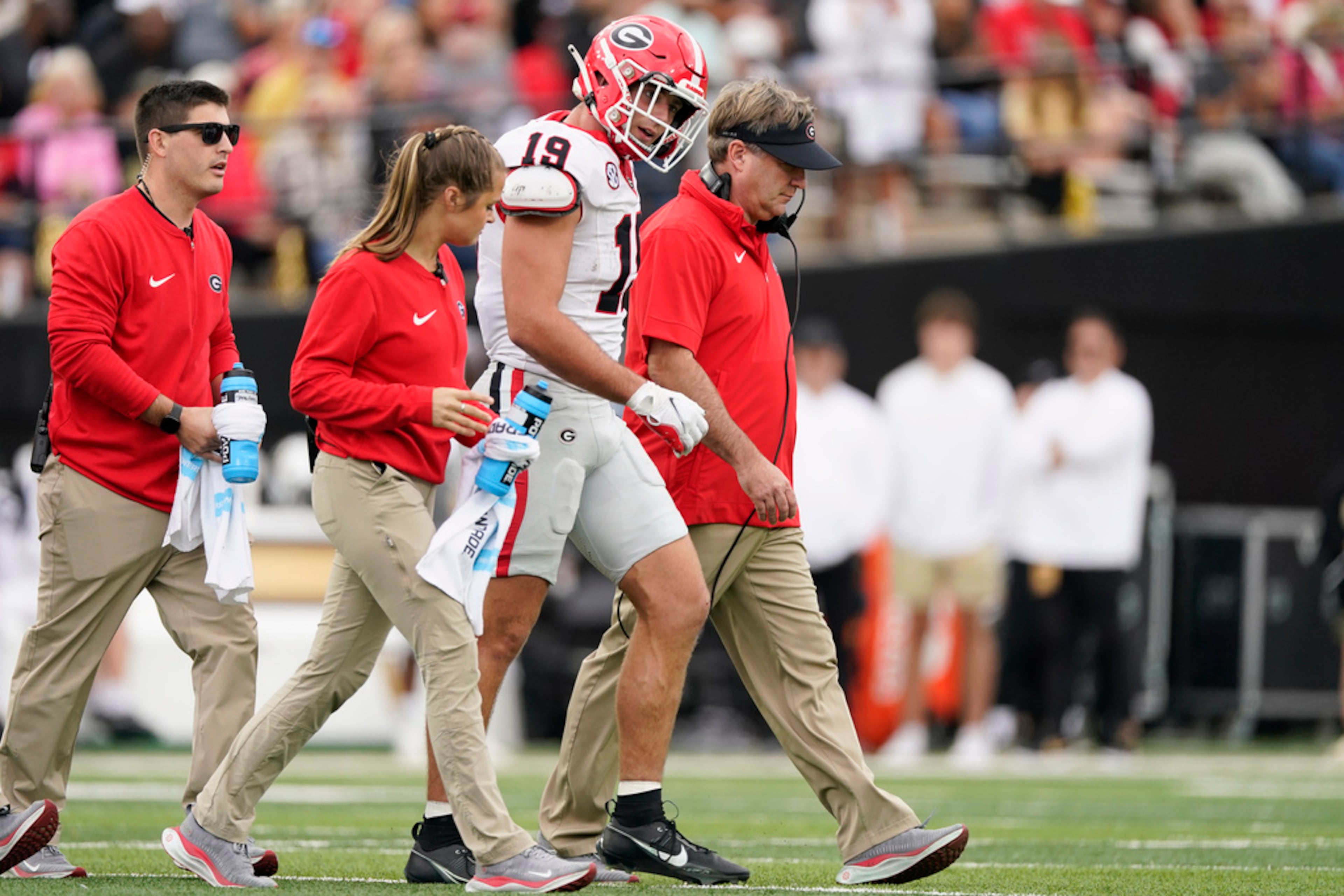 Georgia tight end Brock Bowers (19) walks of the field with head coach Kirby Smart, right, after being injured in the first half of an NCAA college football game against Vanderbilt, Saturday, Oct. 14, 2023, in Nashville, Tenn. Georgia won 37-20. (AP Photo/George Walker IV)