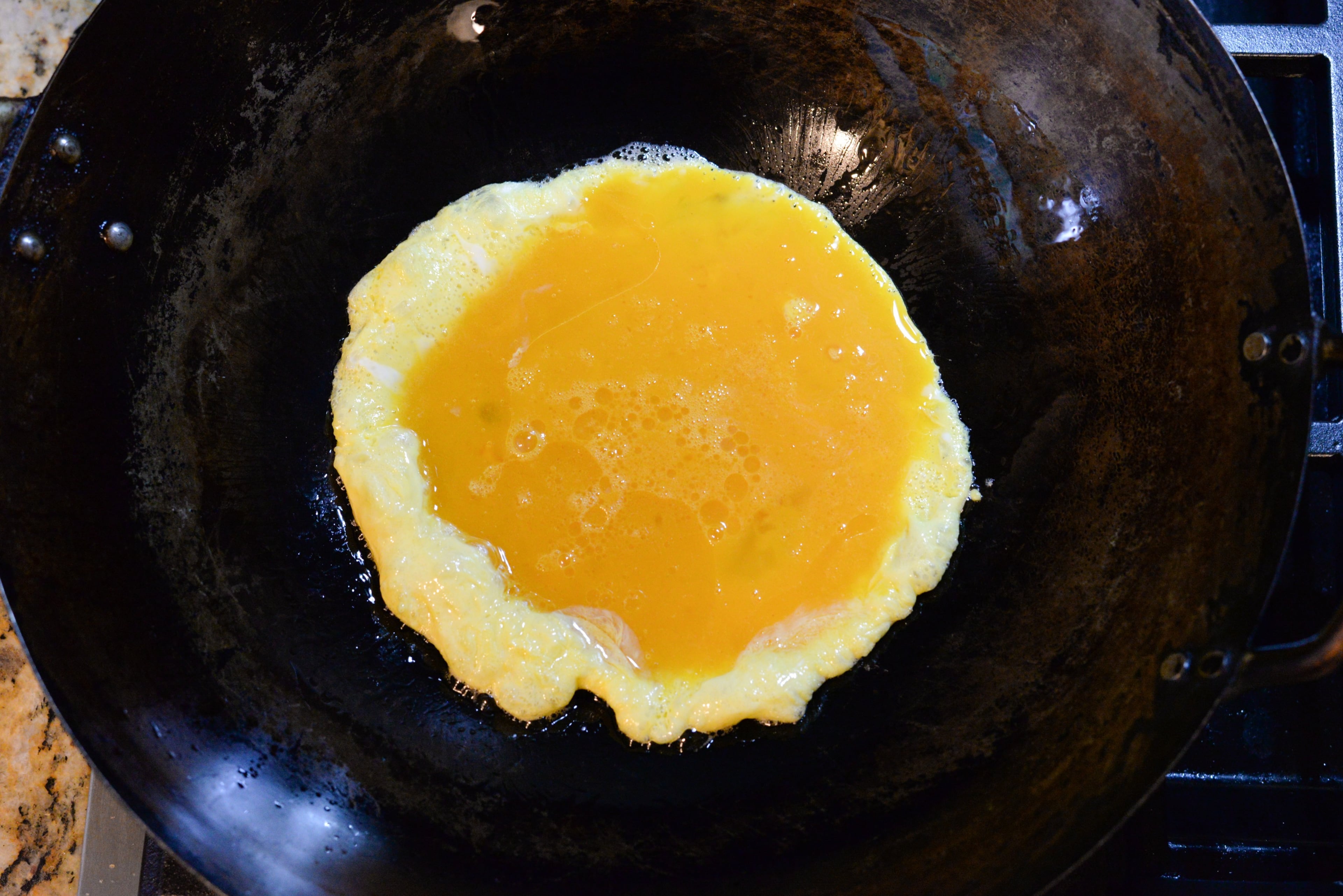 Heat 2 tablespoons corn oil in a wok or skillet over high heat. Once the oil is shimmering, add the egg mixture. Use a spatula to quickly move the eggs around for 30 seconds or until a wet, custardy consistency develops. Transfer eggs to a dish. (Candy Hom for the AJC)