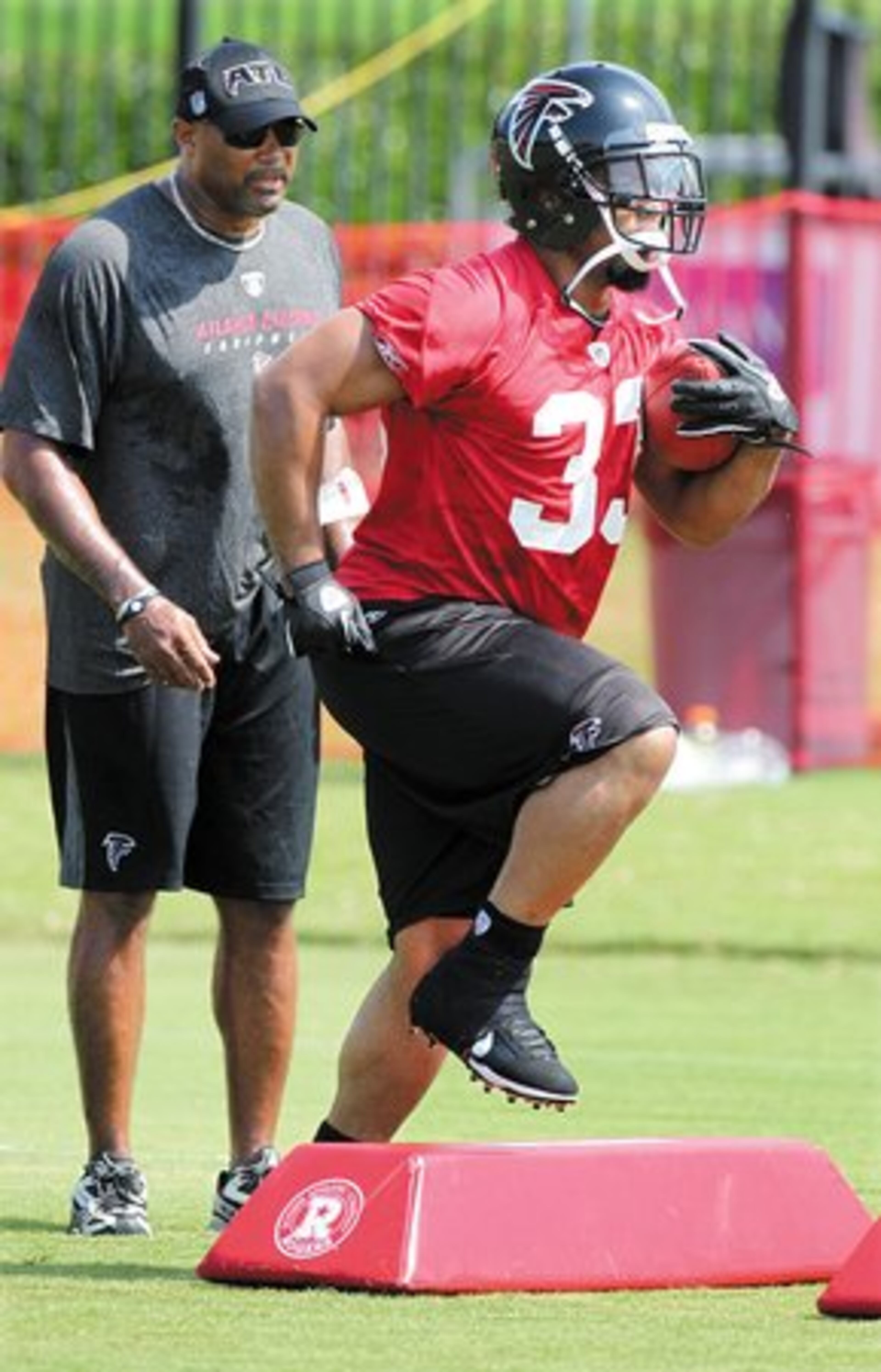 Running back Micheal Turner runs a foot work drill as running backs coach Gerald Brown looks on.