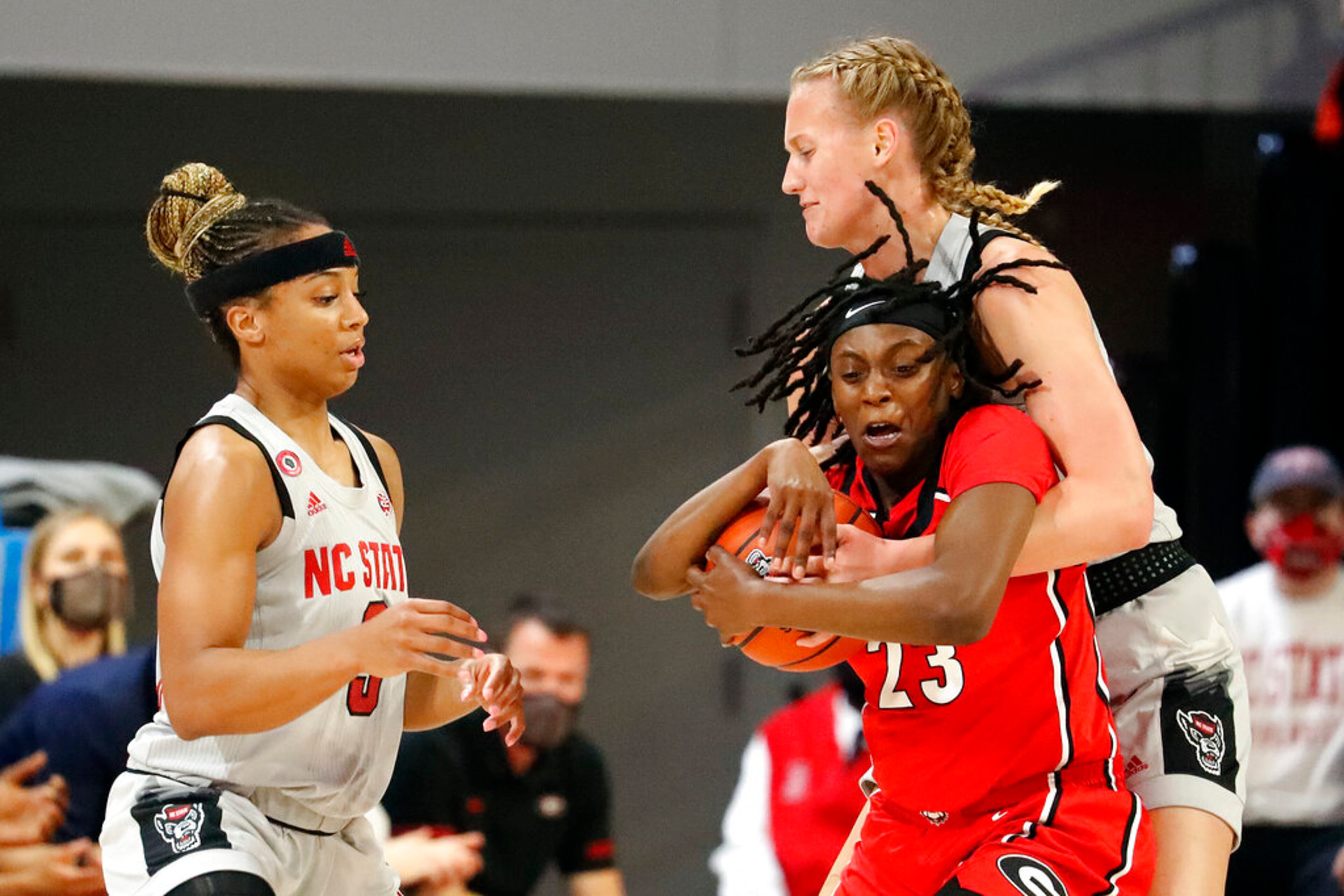 Georgia's Que Morrison (23) tries to steal the ball from North Carolina State's Elissa Cunane, top right, with North Carolina State's Kai Crutchfield (3) watching during the first half of an NCAA college basketball game, Thursday, Dec. 16, 2021, in Raleigh, N.C. Morrison was called for a foul on the play. (AP Photo/Karl B. DeBlaker)