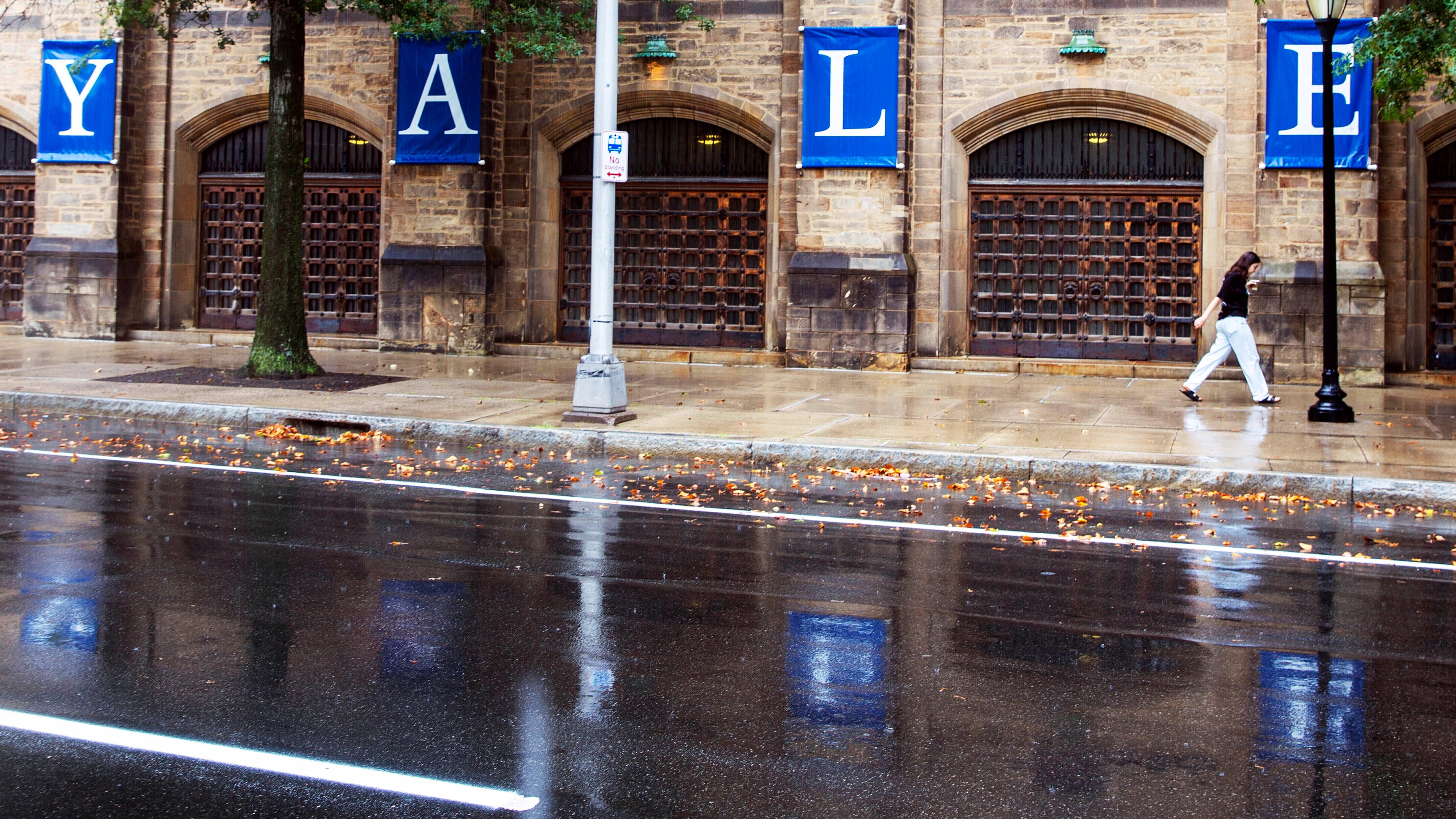 FILE - A woman walks by a Yale sign reflected in the rainwater on the Yale University campus in New Haven, Conn., Aug. 22, 2021. (AP Photo/Ted Shaffrey, File)