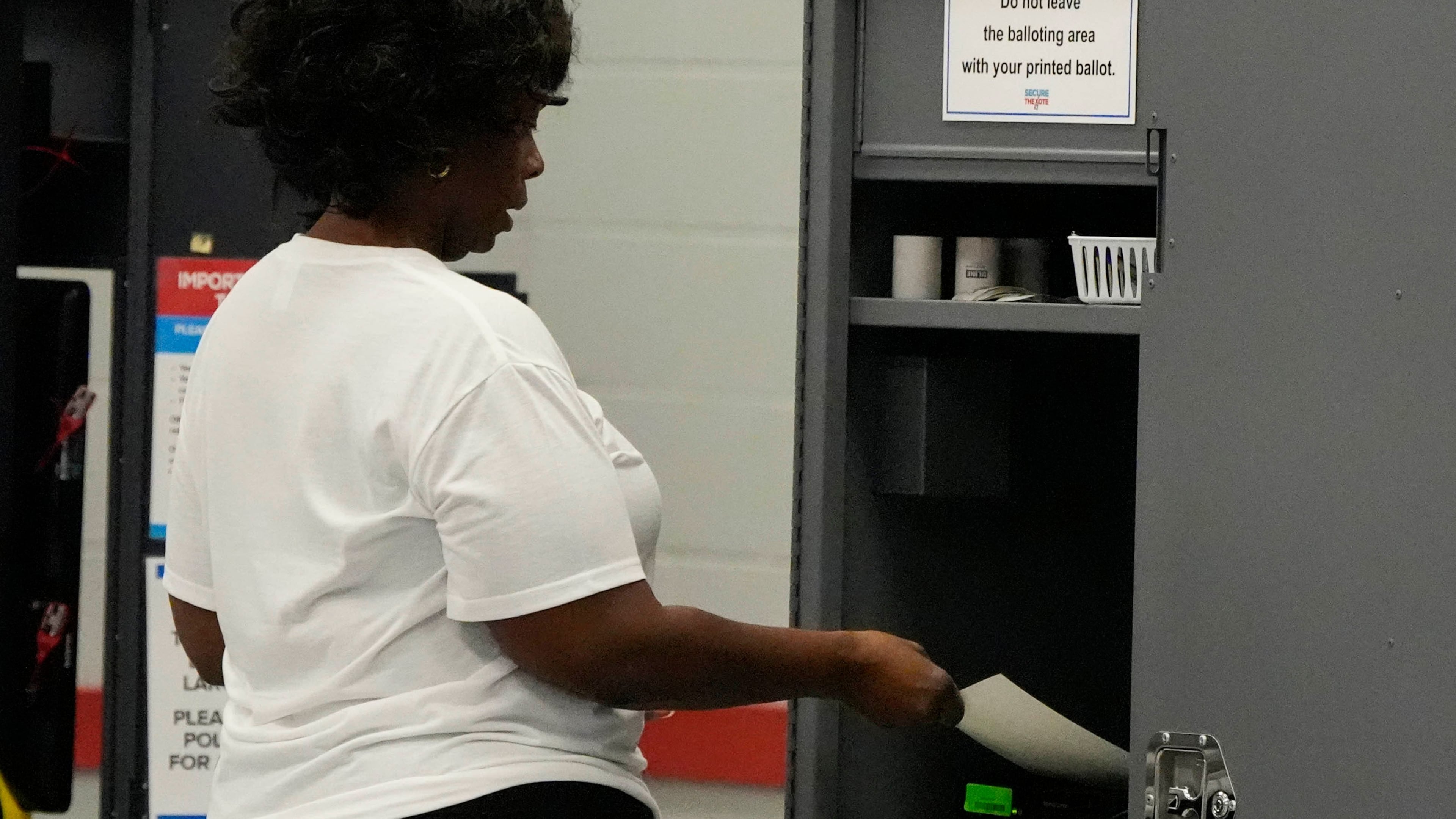 A woman places her paper ballot into a machine after voting in a runoff election at C.T. Martin Recreation Center, Tuesday, June 16, 2026, in Atlanta. (AP Photo/Mike Stewart)
