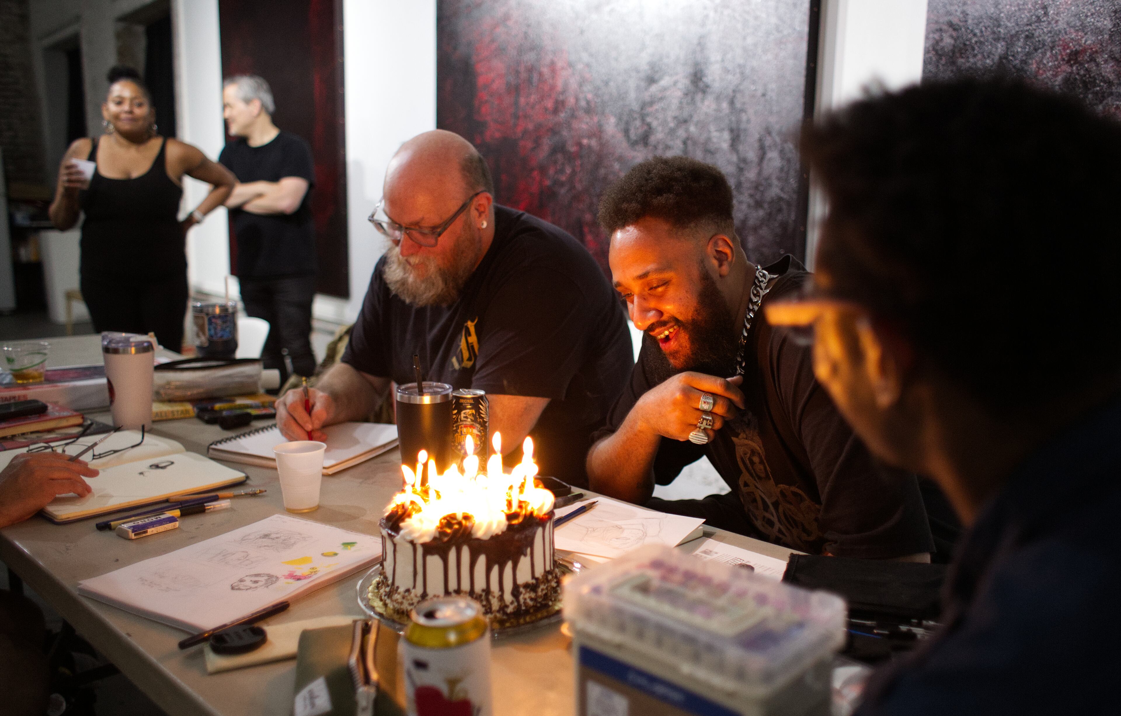 In a sign of the close community enjoyed by the High Contrast artists, a chocolate cake marked the birthdays of participants James Daniel (center) and Mariano Lino (front right) during the July session, with slices shared around the room. (Courtesy of Dustin Timbrook)