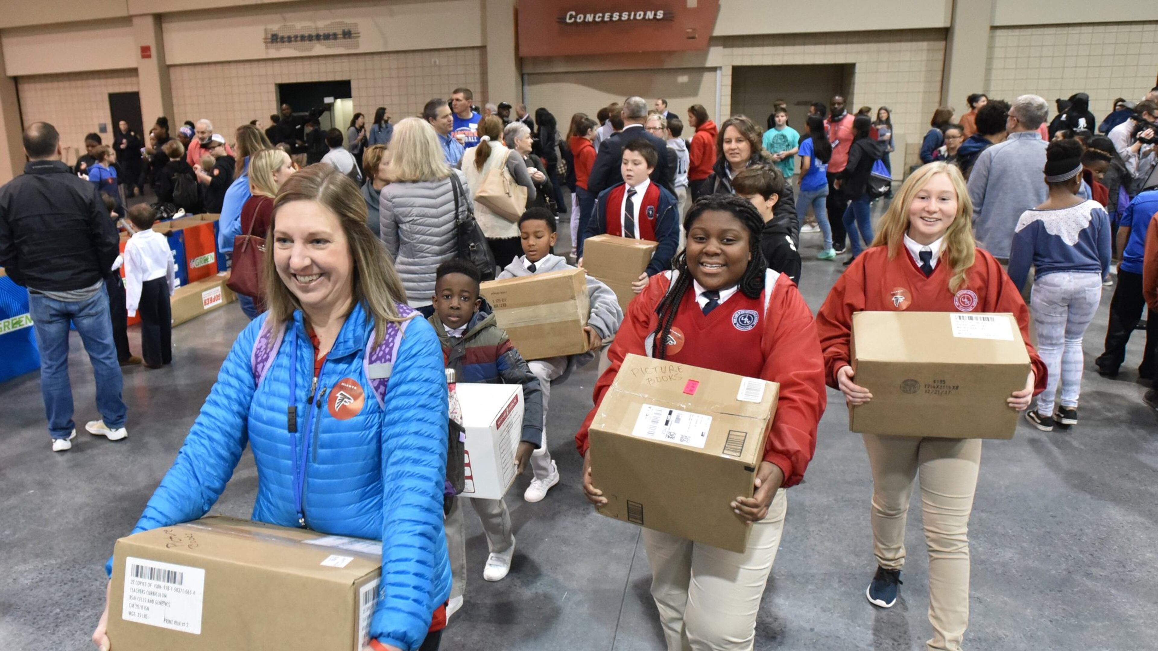 Christine Krabel (foreground), a teacher from Our Lady of Victory School in Tyrone, and her students bring in their donations during the NFL’s Super Kids-Super Sharing project at the Infinite Energy Forum in Duluth. The project started in Atlanta in 2000 and celebrates its 20th anniversary in Atlanta. HYOSUB SHIN / HSHIN@AJC.COM