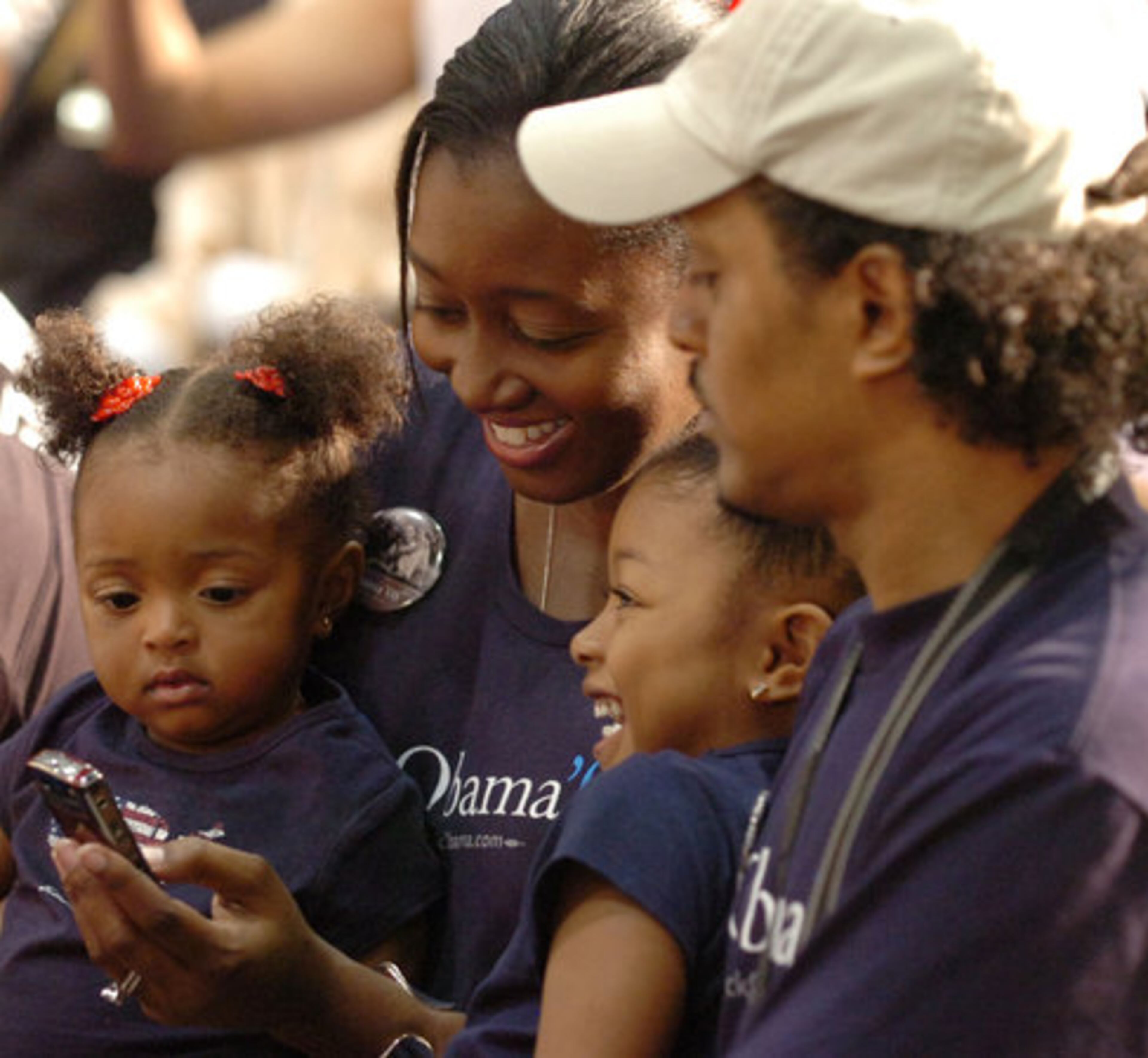 Carlos and Kendra Munoz of Austell brought their children Calah, 4, and Chloe, 15 months, to the town hall meeting. Here, they look at cell phone photos Carlos has just taken.