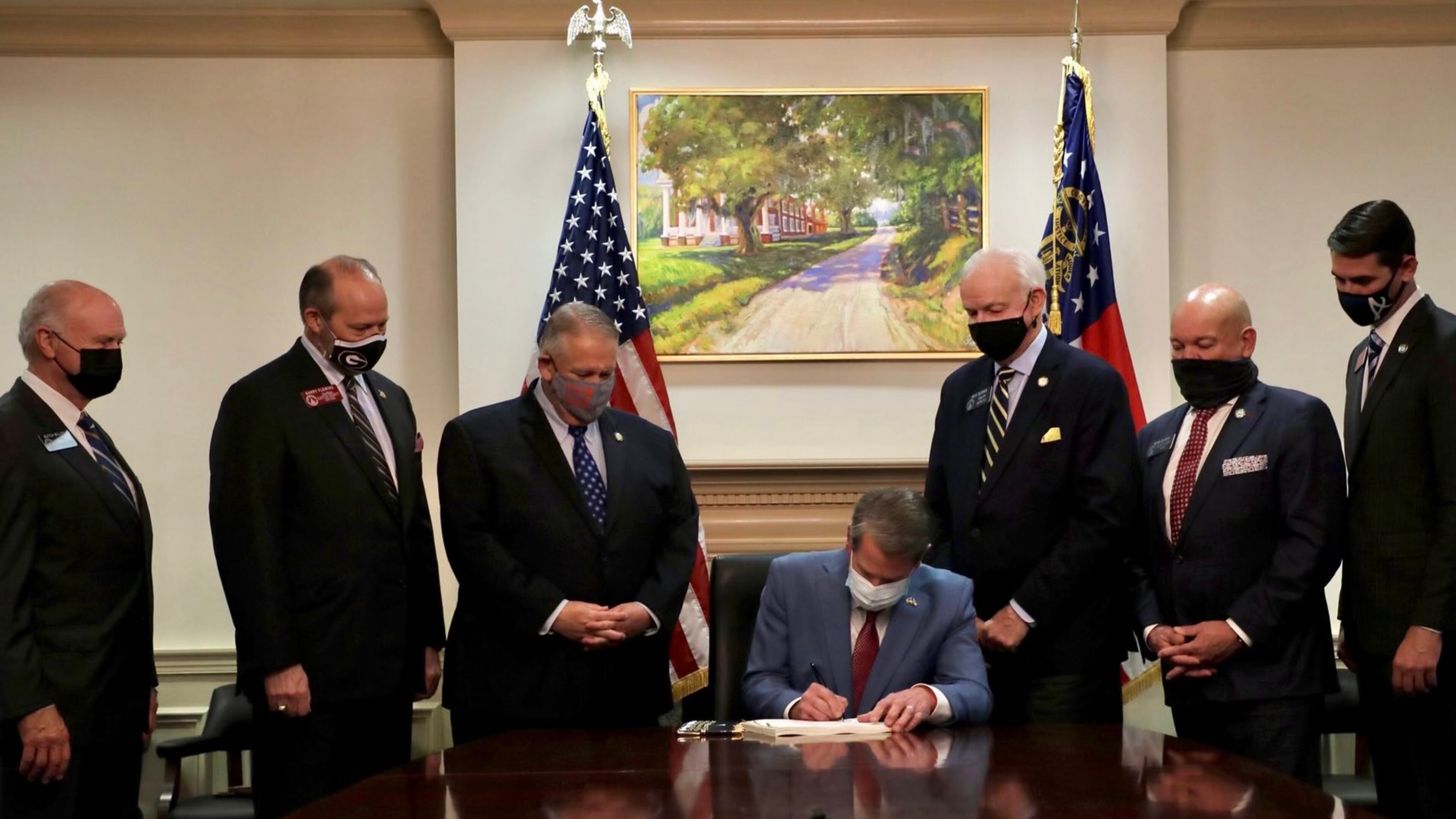 Gov. Brian Kemp signs the elections overhaul into law at the Capitol, flanked by legislative leaders.