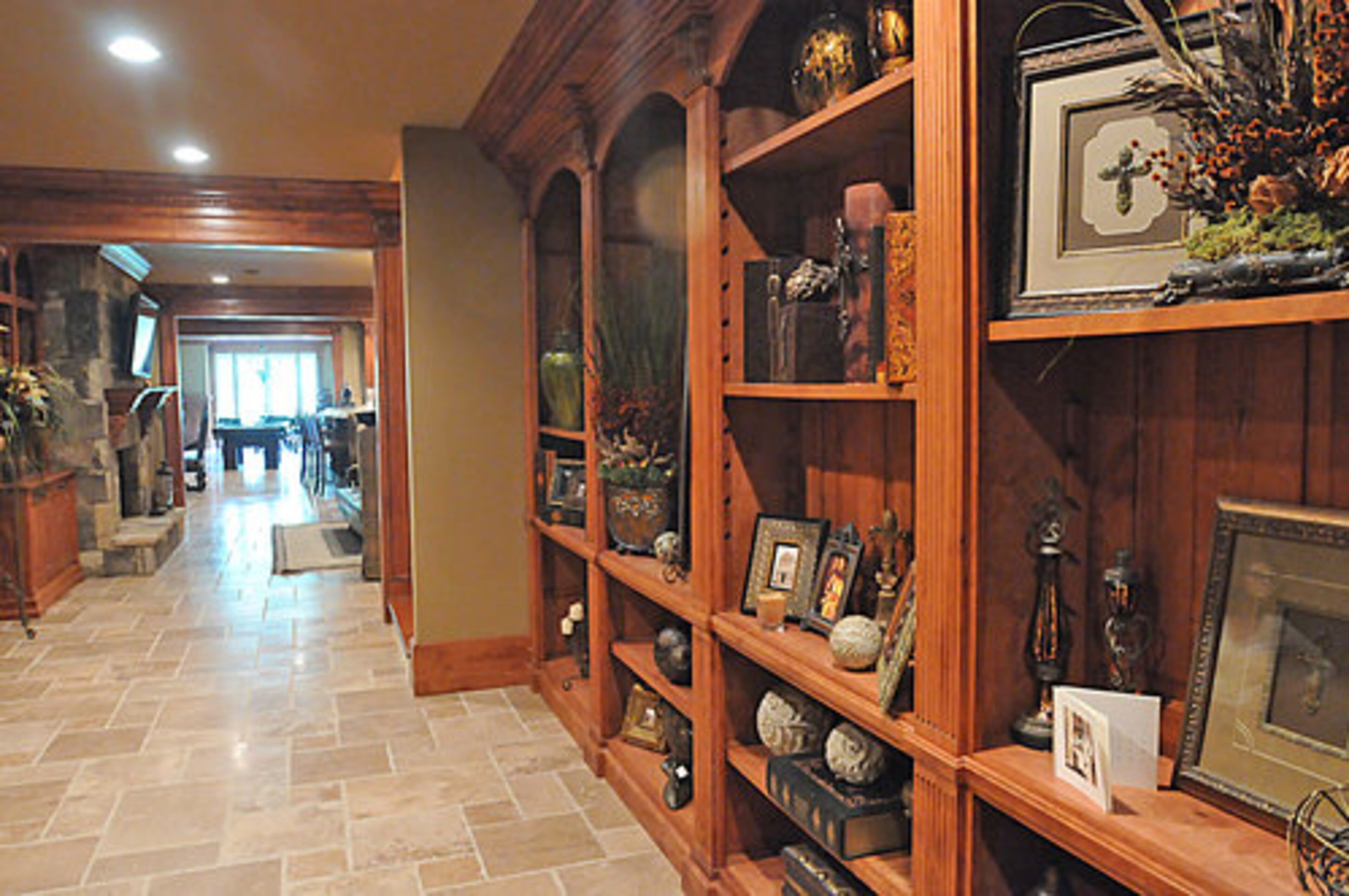 This hallway leads to the family room on the terrace level. Gorgeous wood accents abound, and the shelving unit to the right can be used to display family mementos and other decorative items, as Kendra has done with her own personal flair.