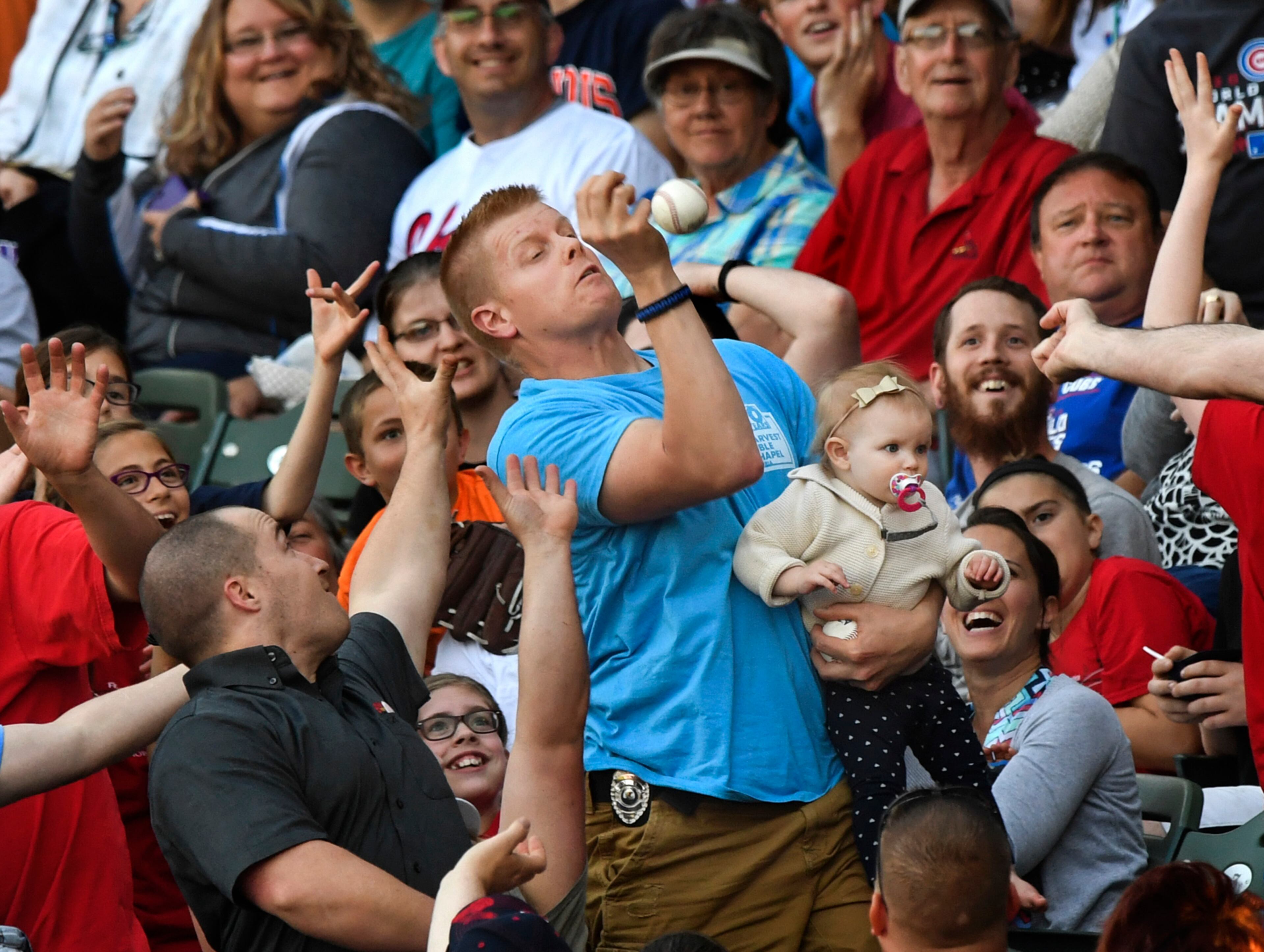 Mark Ehlke of Morton, Ill., holds 1-year-old daughter Elsie while making a catch on a foul ball in the stands during a Class A Midwest League baseball game between the Peoria Chiefs and the South Bend Cubs at Dozer Park in Peoria, Ill., Friday, May 12, 2017. (Ron Johnson/Journal Star via AP)