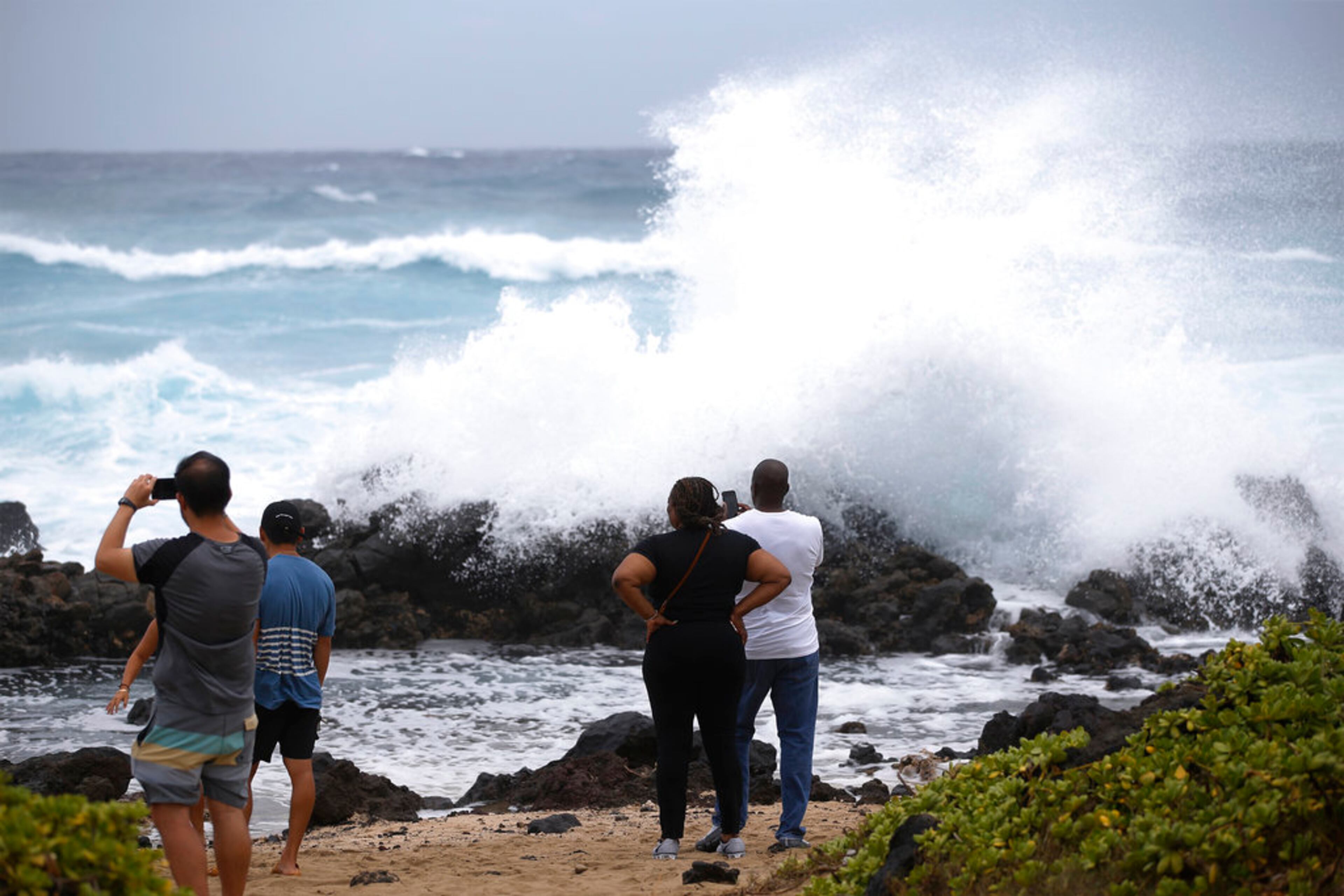 Onlookers watch large waves crash on the rocks at Wawamalu Beach, Friday, Aug. 24, 2018, in Waimanalo, Hawaii. As Hurricane Lane approaches Oahu, large ocean swells have impacted the coastline. (AP Photo/Marco Garcia)