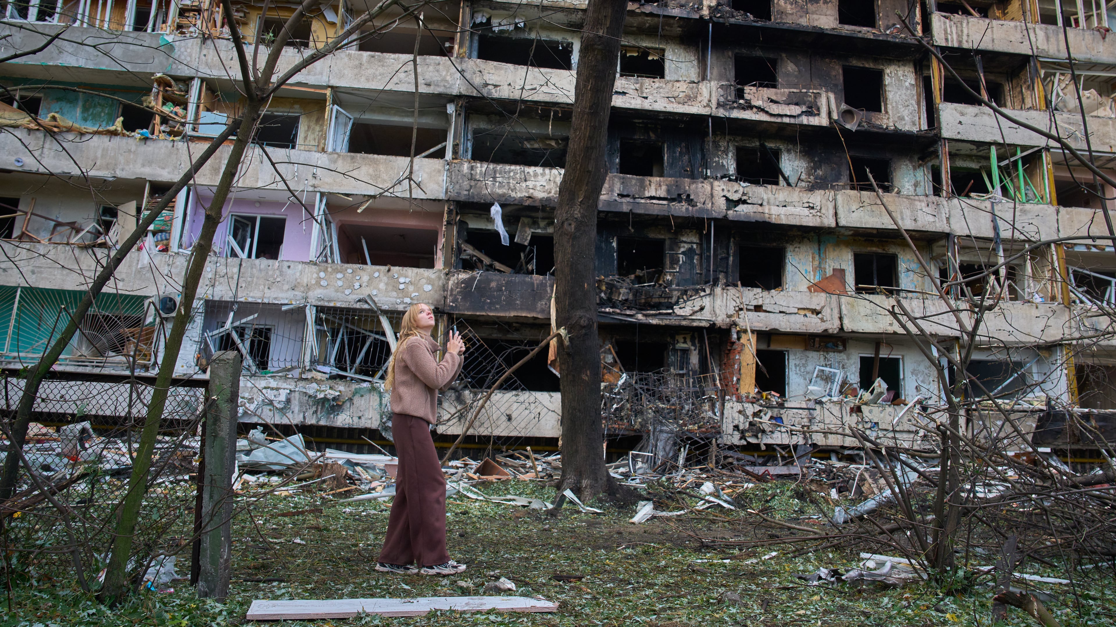 A young woman reacts as she looks at her damaged home after Russia's night missile attack in Kyiv, Ukraine, Wednesday, Oct. 14, 2026. (AP Photo/Efrem Lukatsky)