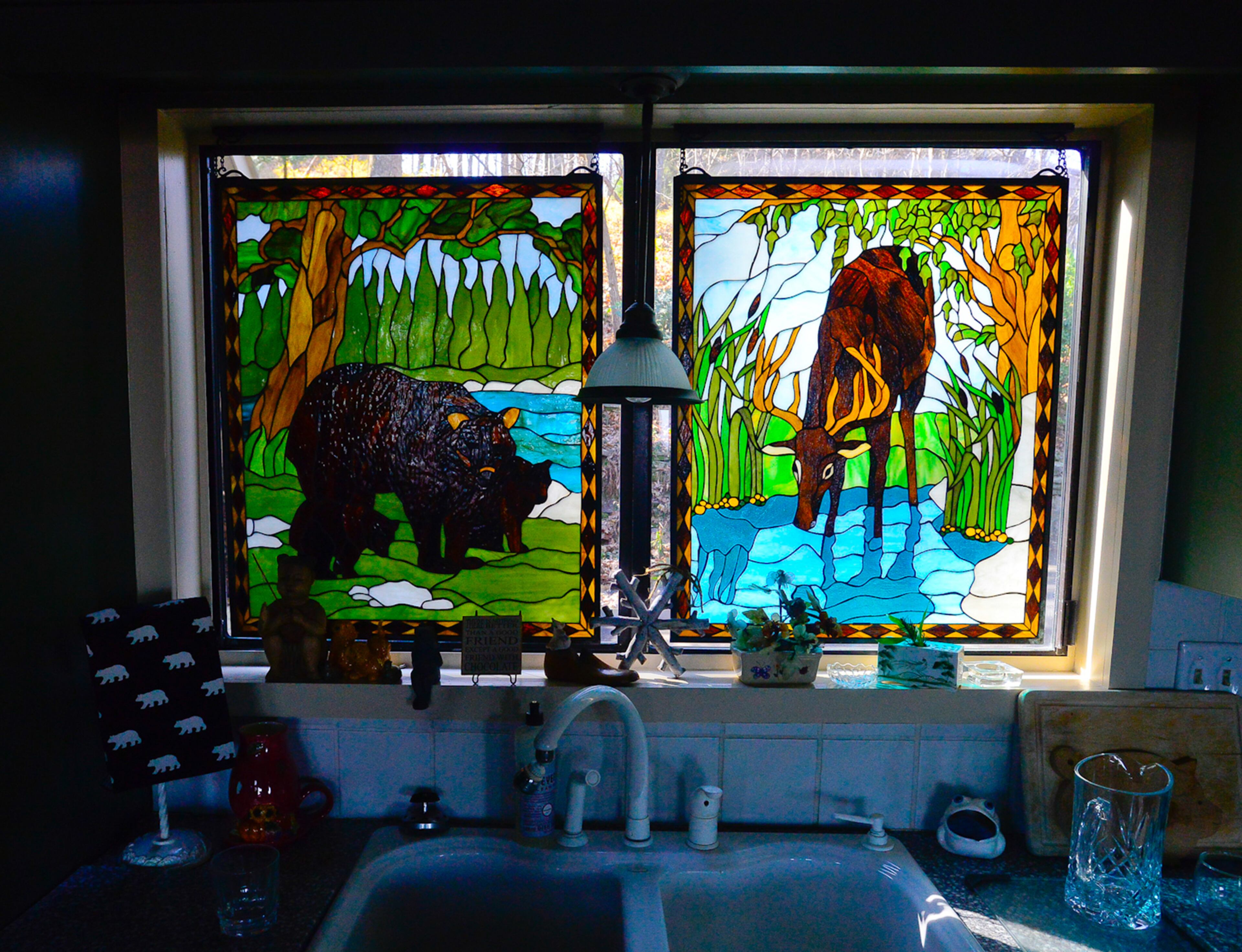In the kitchen, stained glass purchased at AmericasMart Atlanta provides privacy because the window overlooks the driveway. The stained glass still allows light to enter the kitchen and the animal figures can be seen from inside and outside.