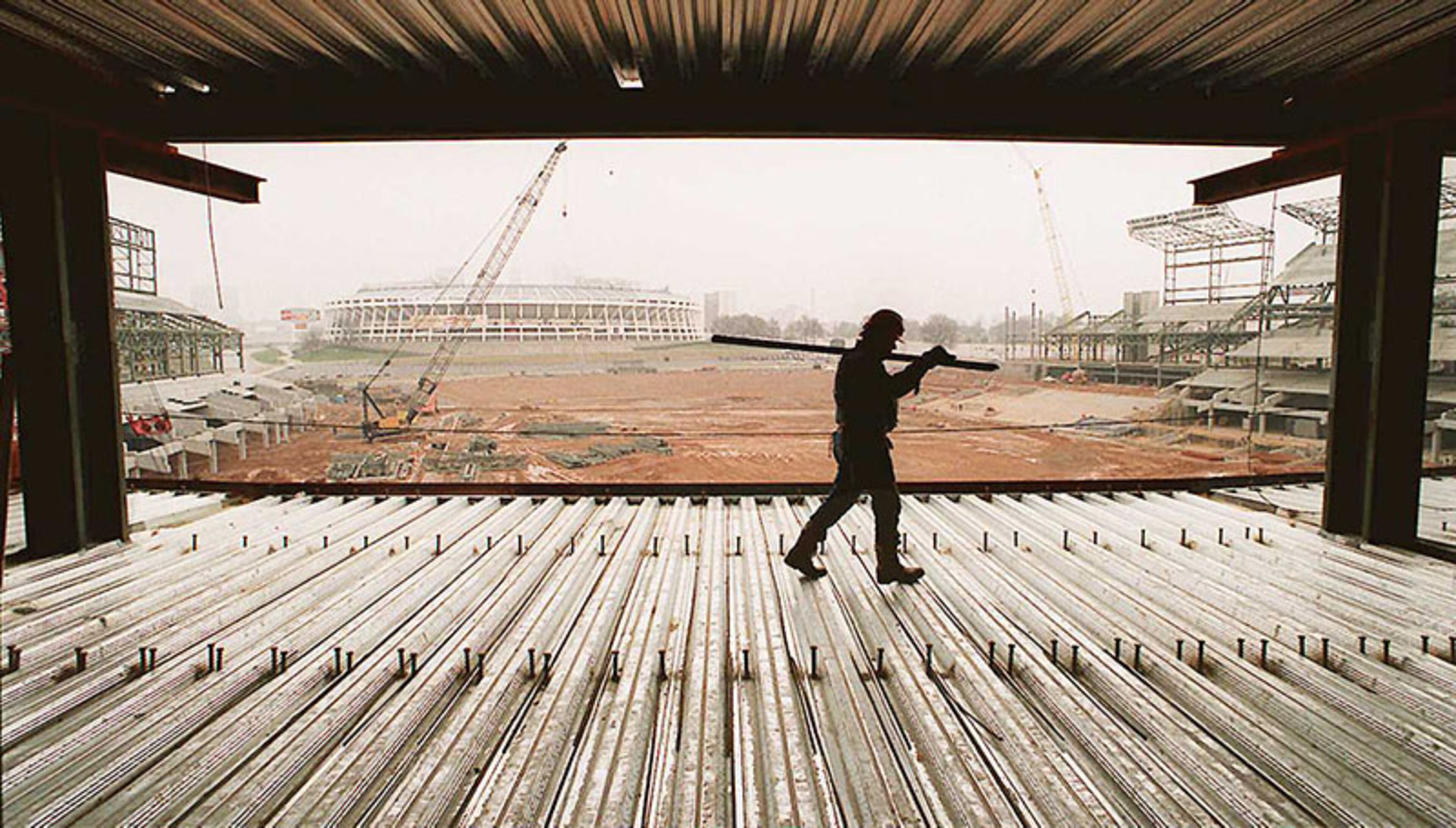 And iron worker is silhouetted against a foggy Atlanta skyline as he walks across what will be the floor in the press box section of the Olympic Stadium in Atlanta. The arena, which cost $209 million to build, was retrofitted for the Braves following the Olympic Games.