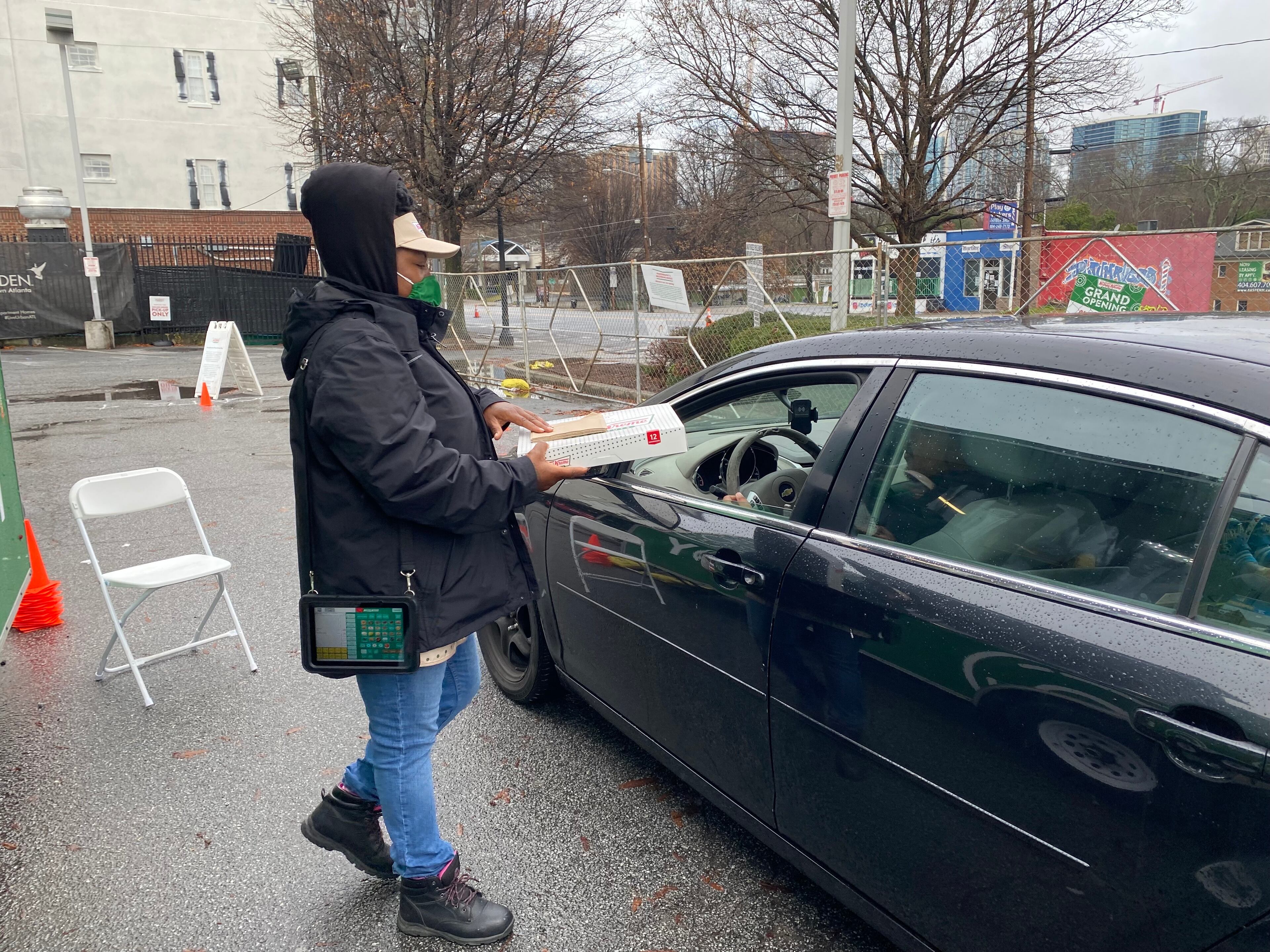 Lavenus Fulton hands a customer an order of Krispy Kreme doughnuts at the pop-up location on Ponce de Leon in Midtown Atlanta. Ligaya Figueras/ligaya.figueras@ajc.com