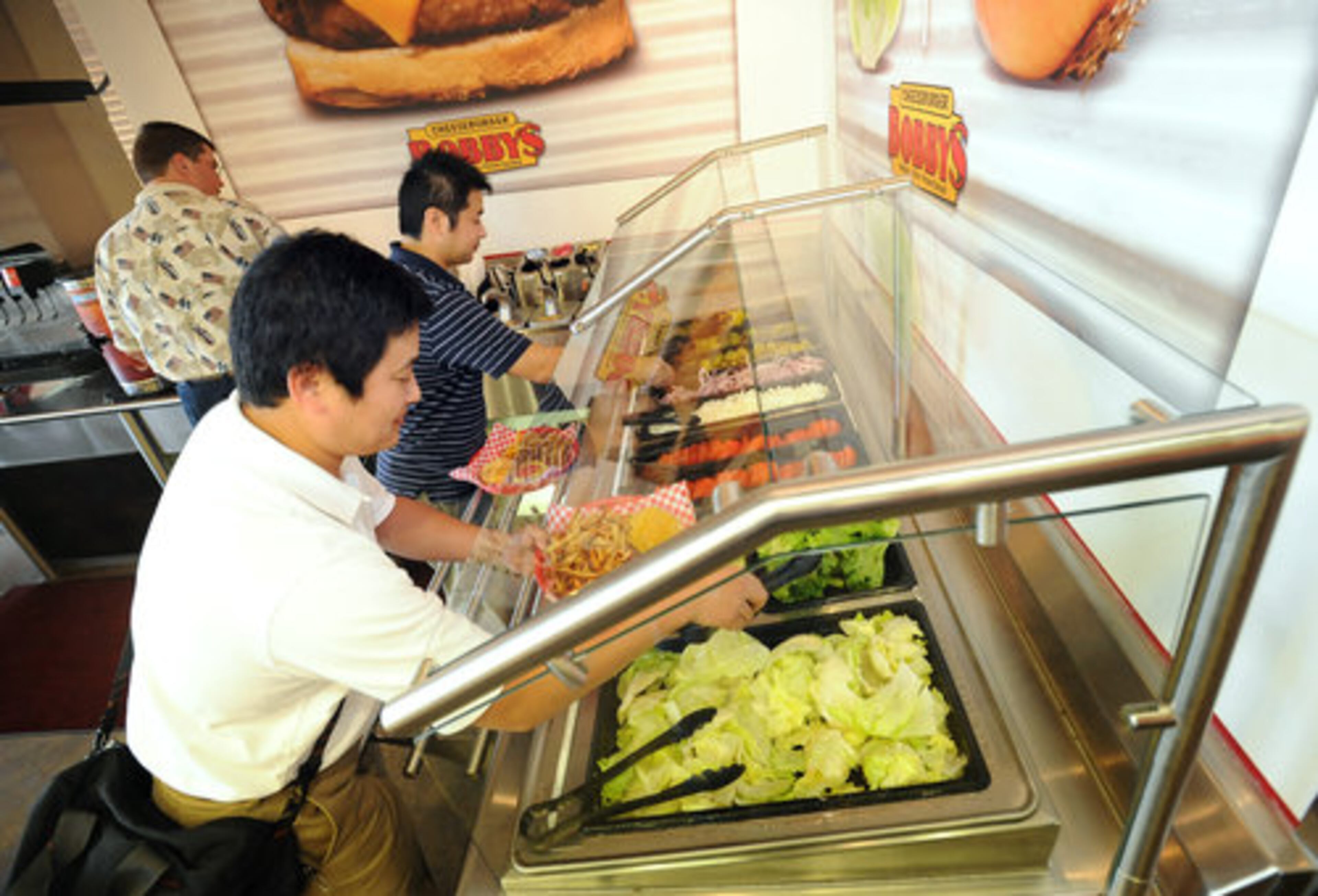 Patrons Yasuhito Oda (foreground) and Murakami Shinsuke customize their burgers. Prices for a combo range from $7 to $9.