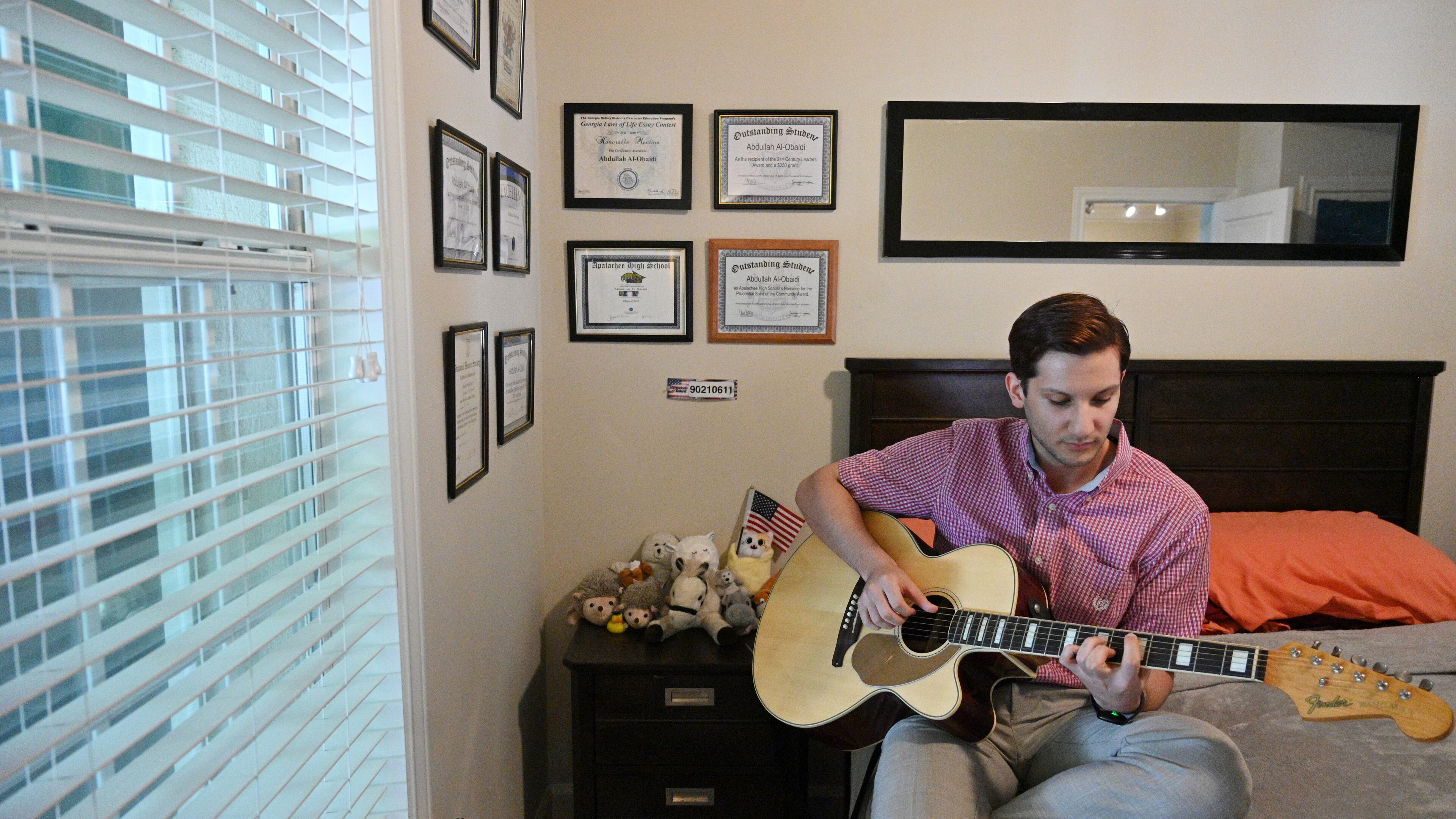 Abdallah Al-Obaidi, who is an Emory student and an Iraqi refugee, plays his guitar at his apartment in Decatur on Thursday, June 17, 2021. (Hyosub Shin / Hyosub.Shin@ajc.com)