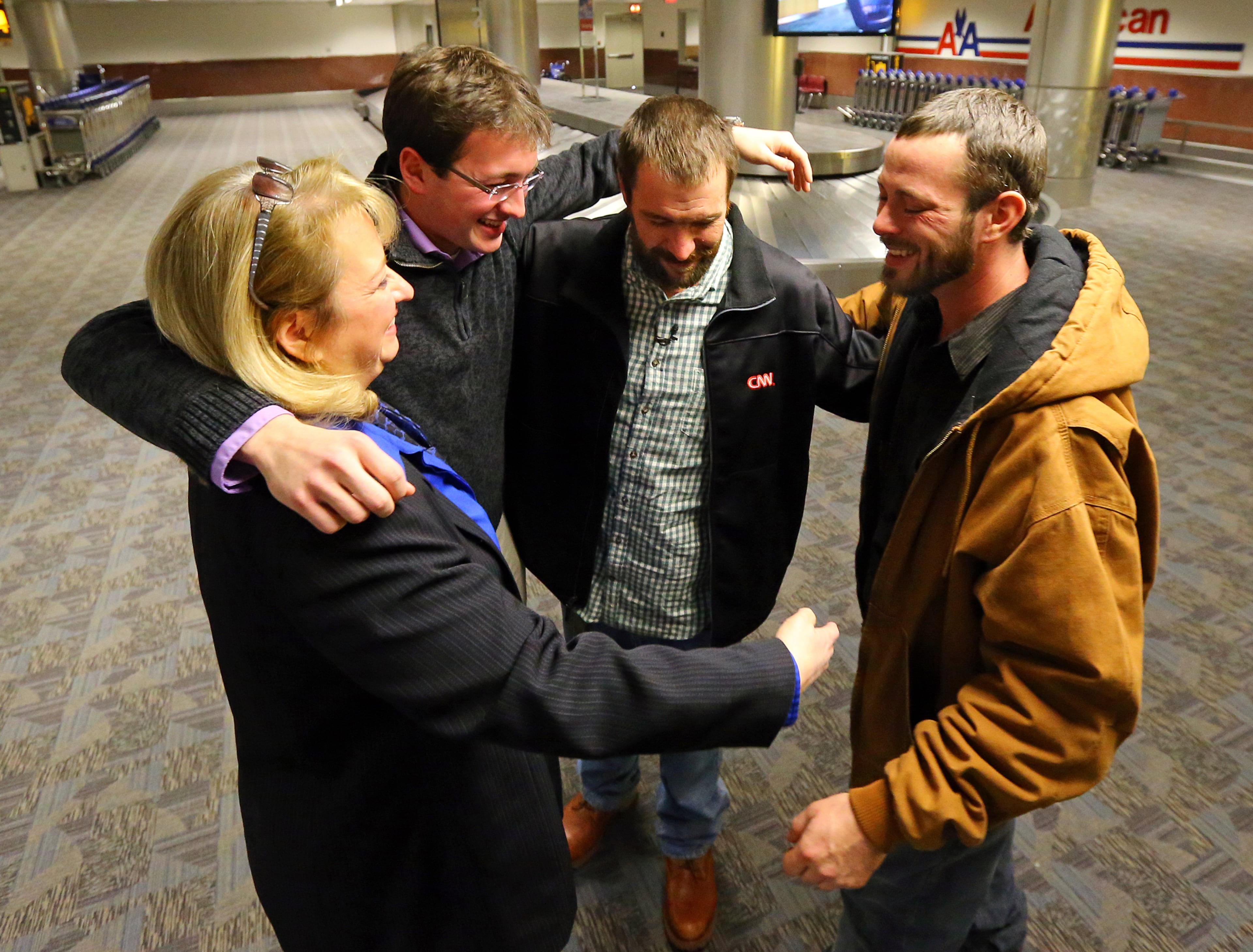 Joel Hartman, the homeless man who returned a woman's wallet he found while digging through trash hoping to find someone's leftover meal, is reunited with his family at Hartsfield-Jackson International Airport for Thanksgiving on Nov. 28, 2013, in Atlanta. His stepmother Deanna Rodecki (from left), brother Andrew Rodecki, Joel Hartman, and his brother Erick Hordos embrace at baggage claim for the first time in a decade.