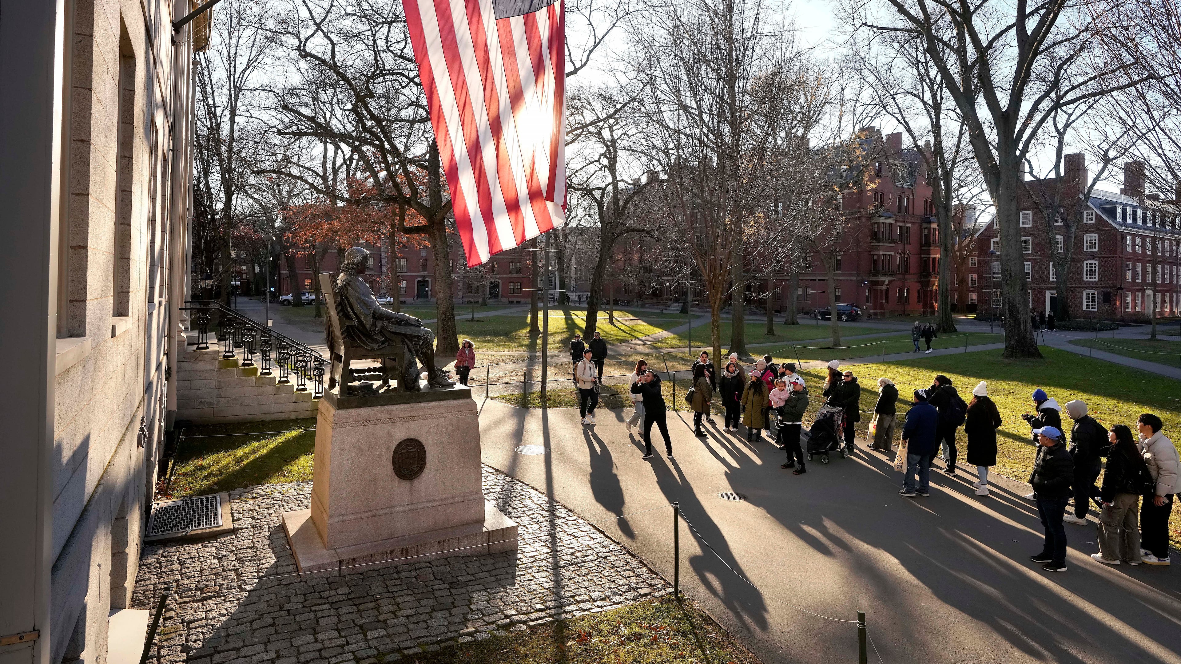 FILE - People take photos near a John Harvard statue, left, on the Harvard University campus, Jan. 2, 2024, in Cambridge, Mass. r. (AP Photo/Steven Senne, File)
