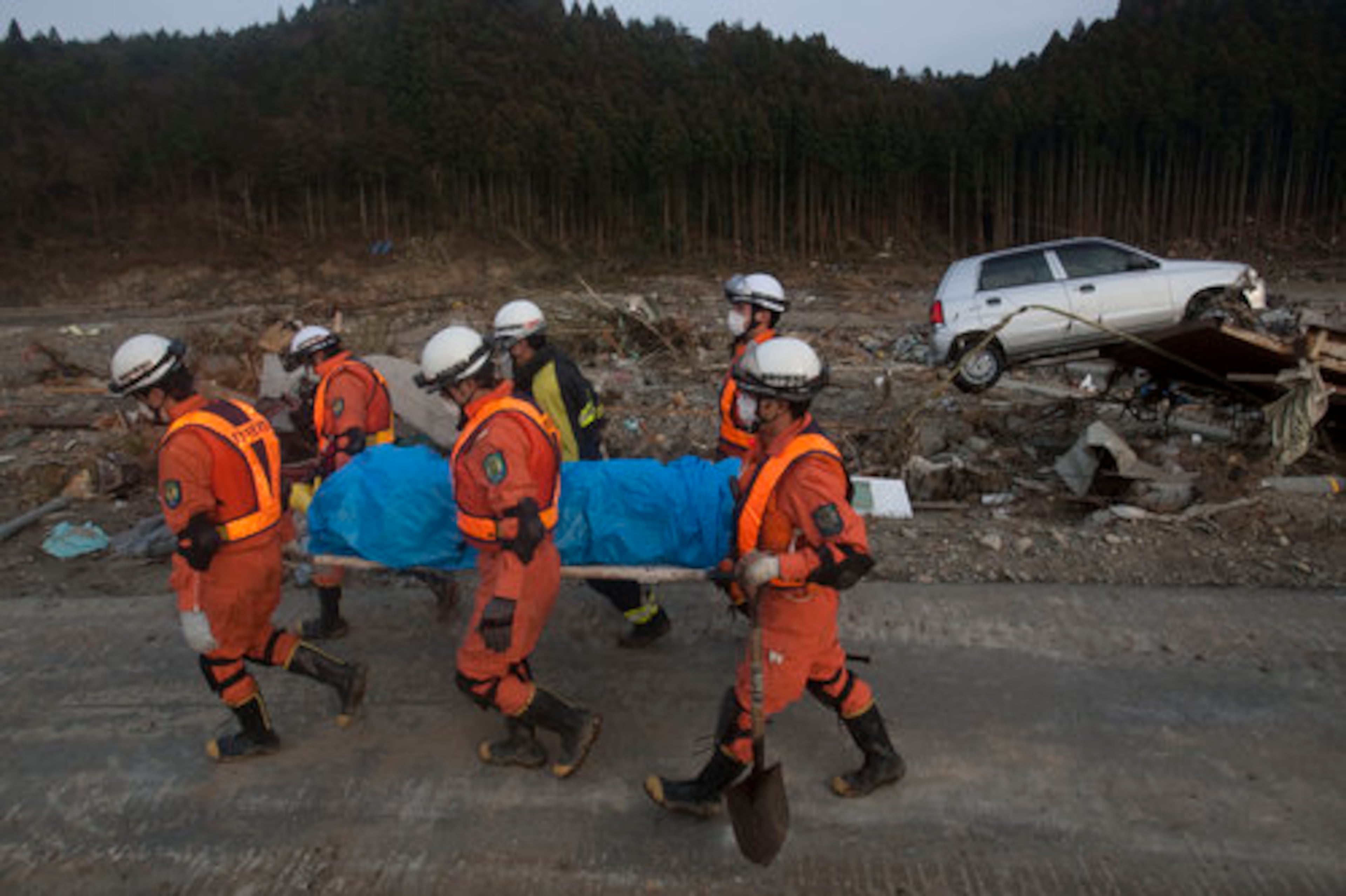 Japanese rescue team members carry the body of a man from the village of Saito, in northeastern Japan, Monday, March 14, 2011.