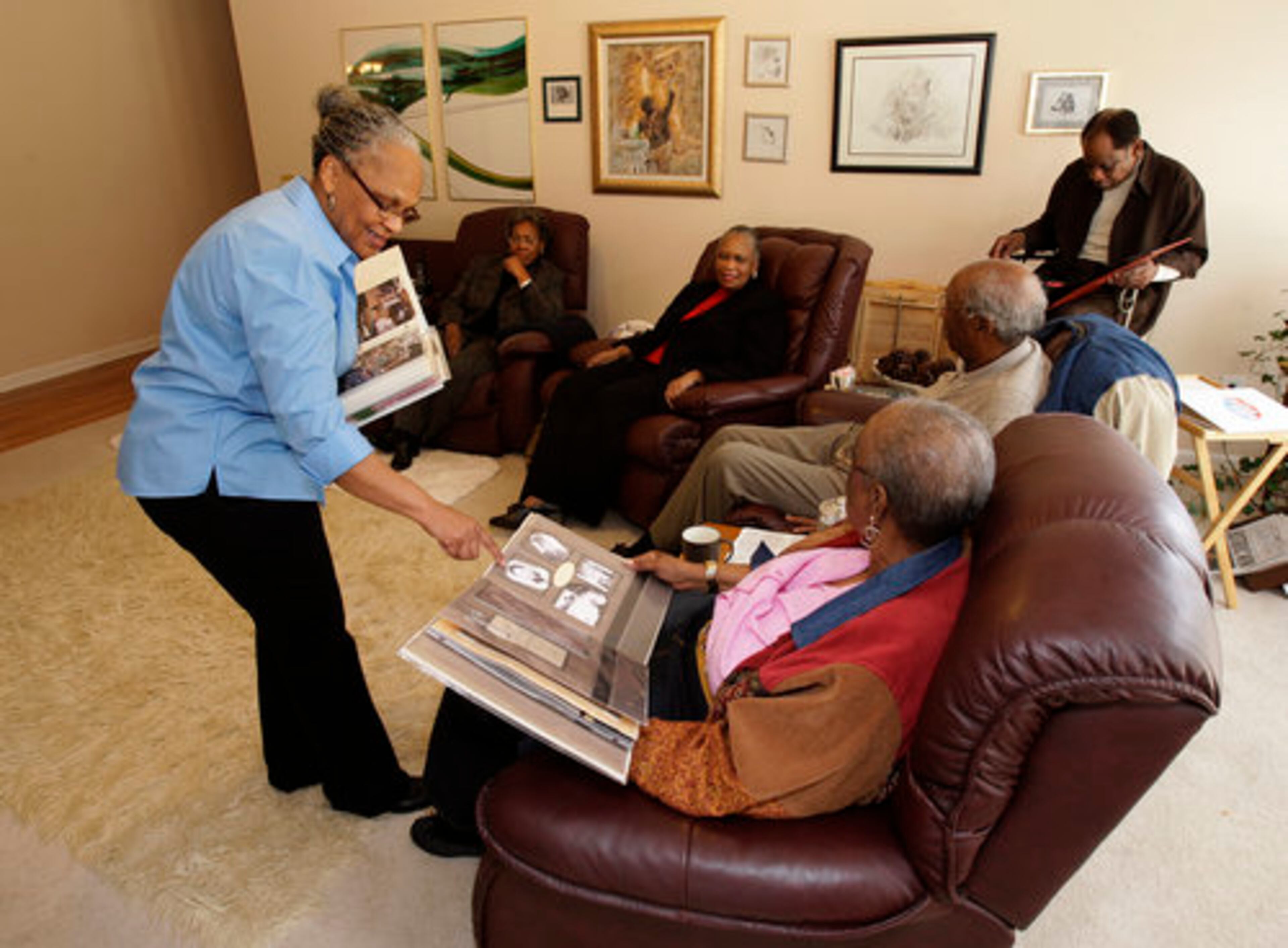 Marcia Glenn Hunter (standing), the former mayor of Lithonia, looks over family albums with her sisters and brothers.