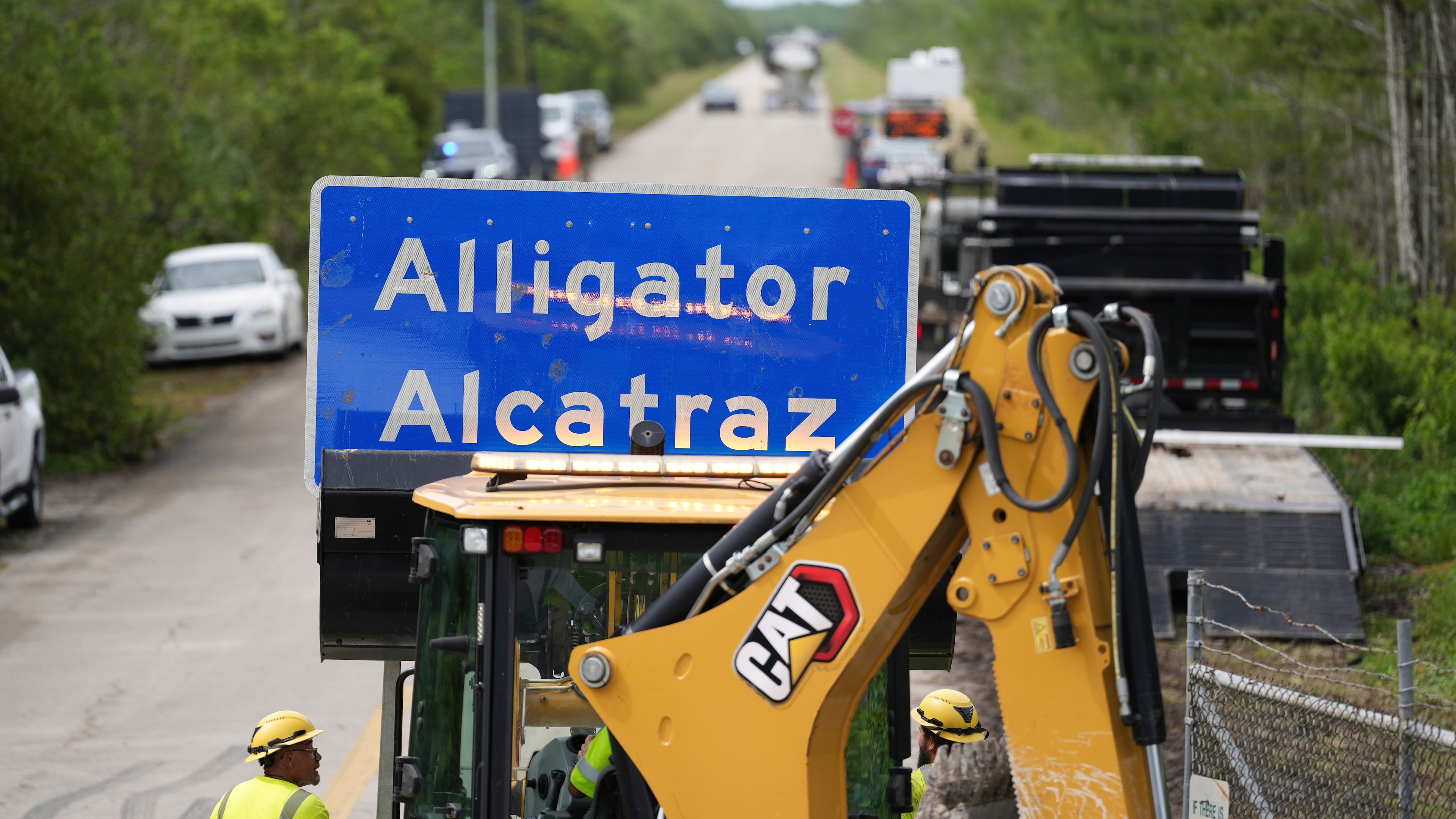 FILE - A loader holds a sign reading "Alligator Alcatraz" in its bucket as workers install it at the entrance to a new migrant detention facility at Dade-Collier Training and Transition facility, July 3, 2025, in Ochopee, Fla. (AP Photo/Rebecca Blackwell)