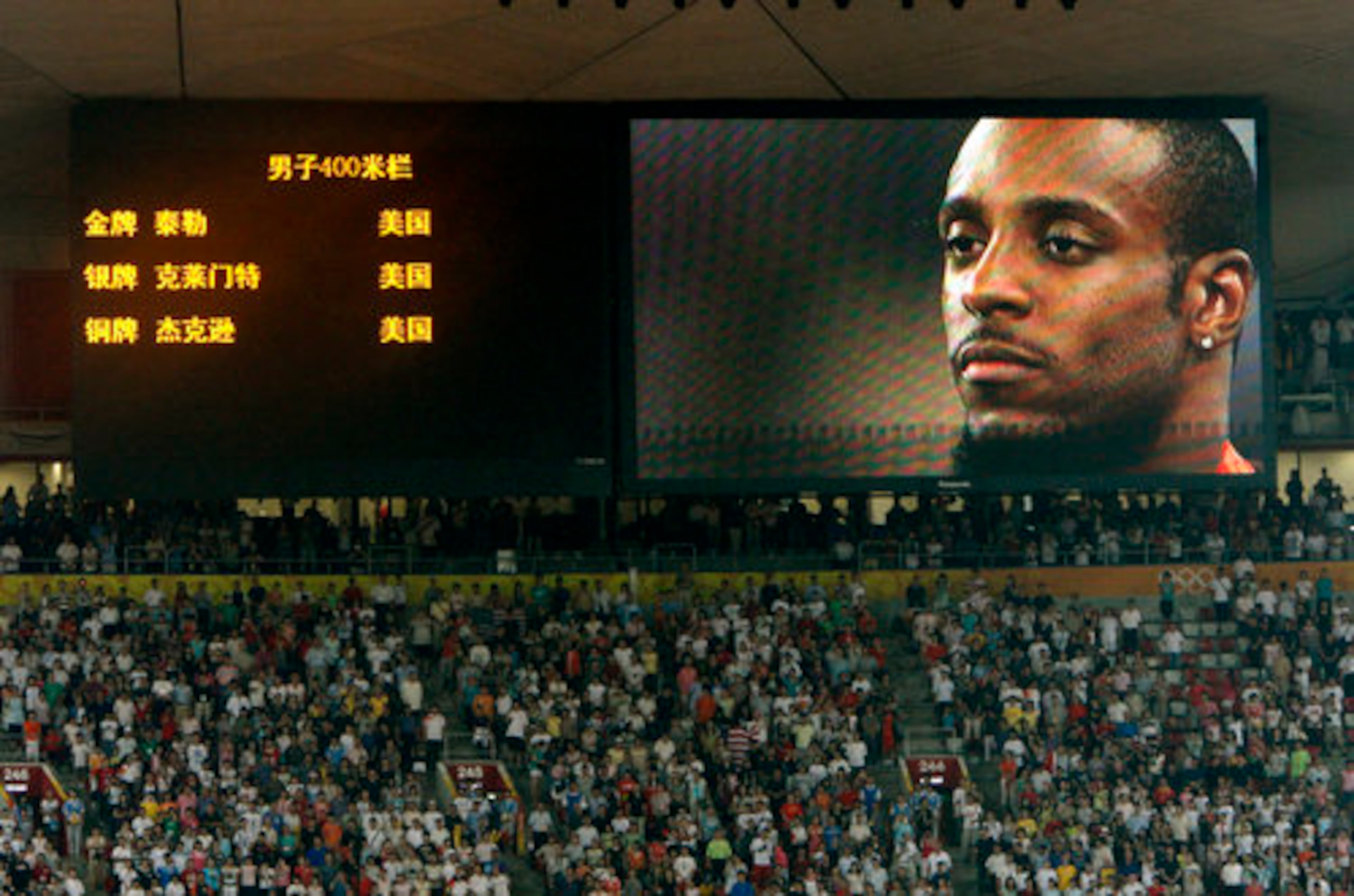 Taylor appears on the big screen as he receives his gold medal in Beijing.