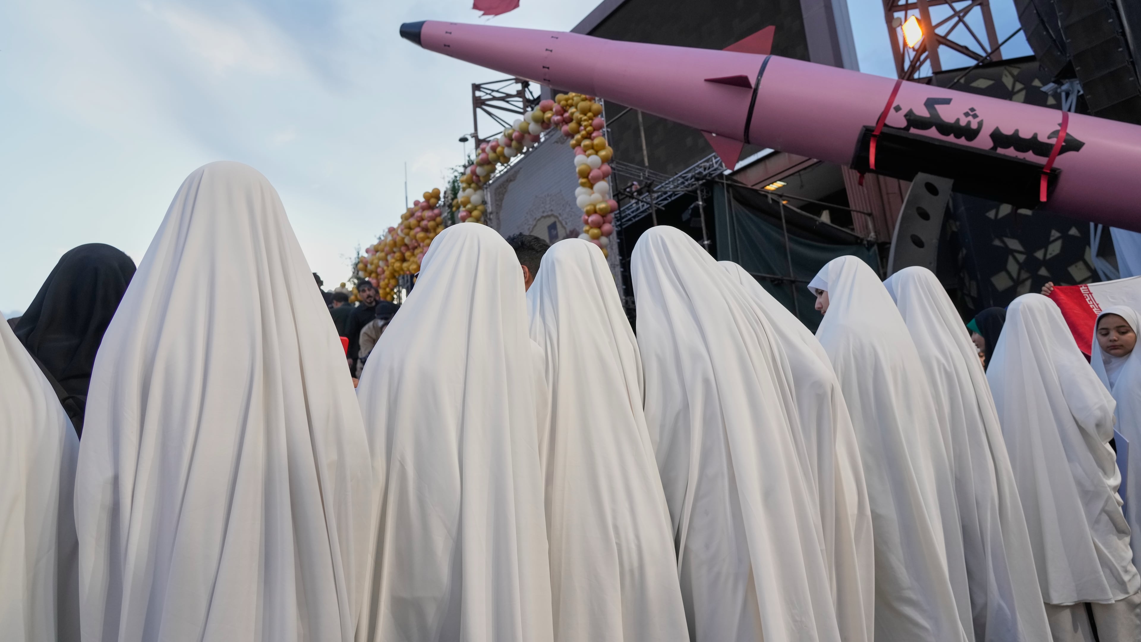 A group of girls stand beside a "Khaybar-buster" missile during a mass wedding ceremony for couples participating in the "Janfada" ("Sacrifice for Iran") pro-government campaign in Tehran, Iran, Monday, May 18, 2026. (AP Photo/Vahid Salemi)